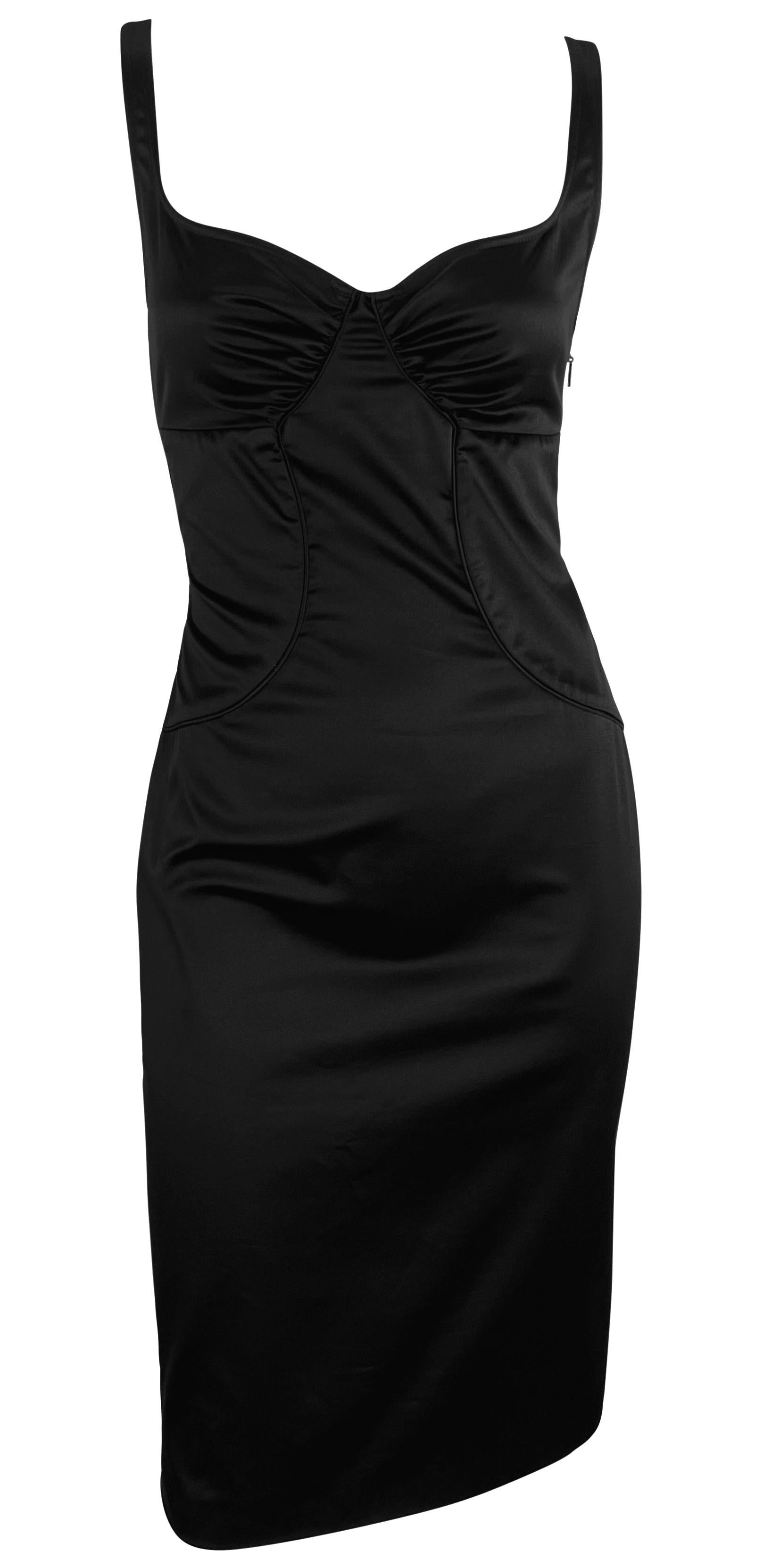 Tom Ford designed this darling little black Gucci dress in 2003. This timeless knee-length piece features a sweetheart neckline, thin shoulder straps, and an exposed back adorned with a knot accent. It includes a small slit at the back and is