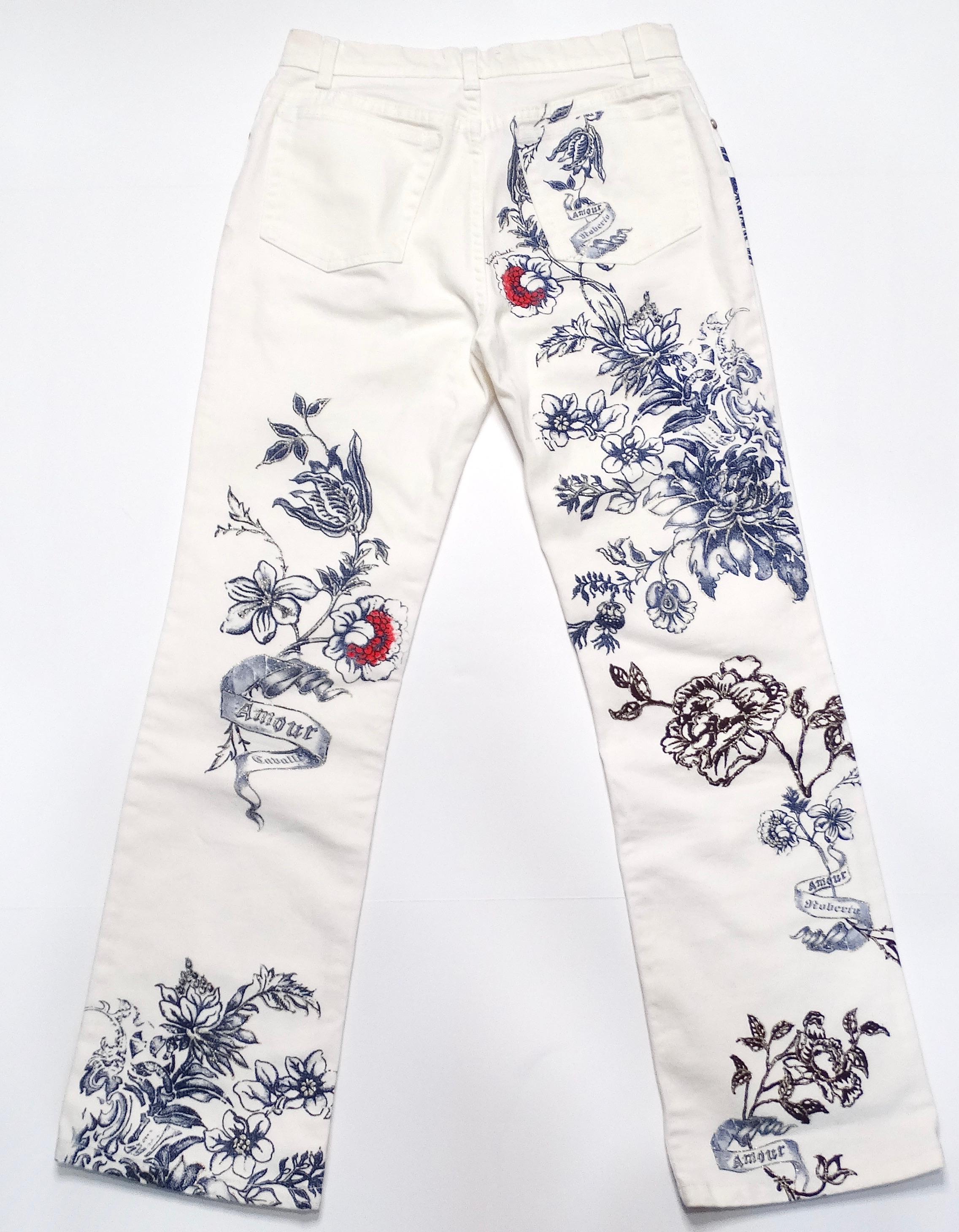 These 2003 Roberto Cavalli white tattoo style print jeans embody the rebellious and glamorous aesthetic of the era. The iconic white background is adorned with intricate, blue tattoo-inspired graphics, giving them a striking and unique look. These