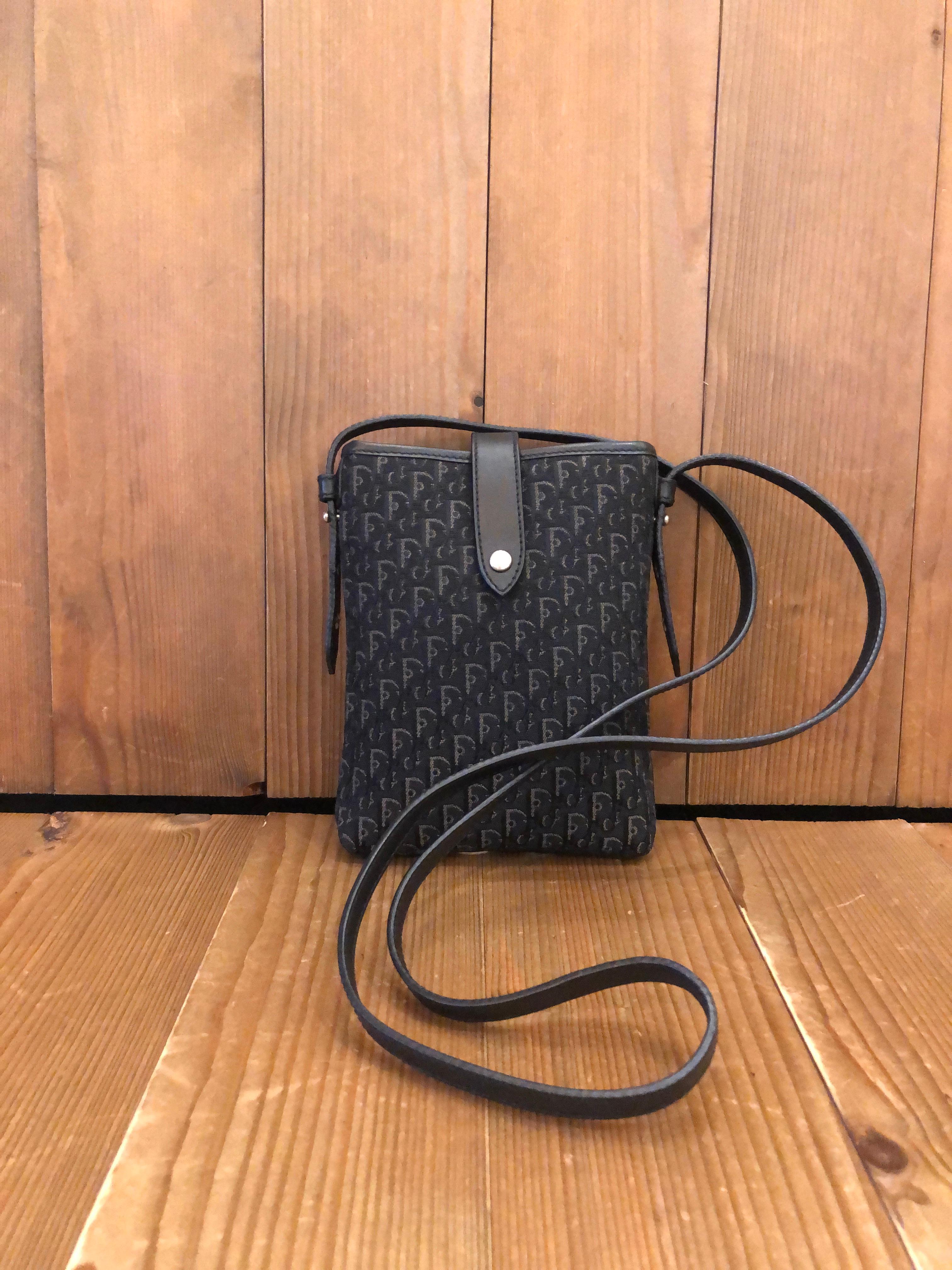2003 Christian Dior crossbody cell phone pouch in black trotter jacquard and smooth leather in black. Top cross over belt closure with snap fastening. Made in Italy. Measures approximately 7 x 5 x 0.75 inches Strap drop 21 inches.

Condition: Minor