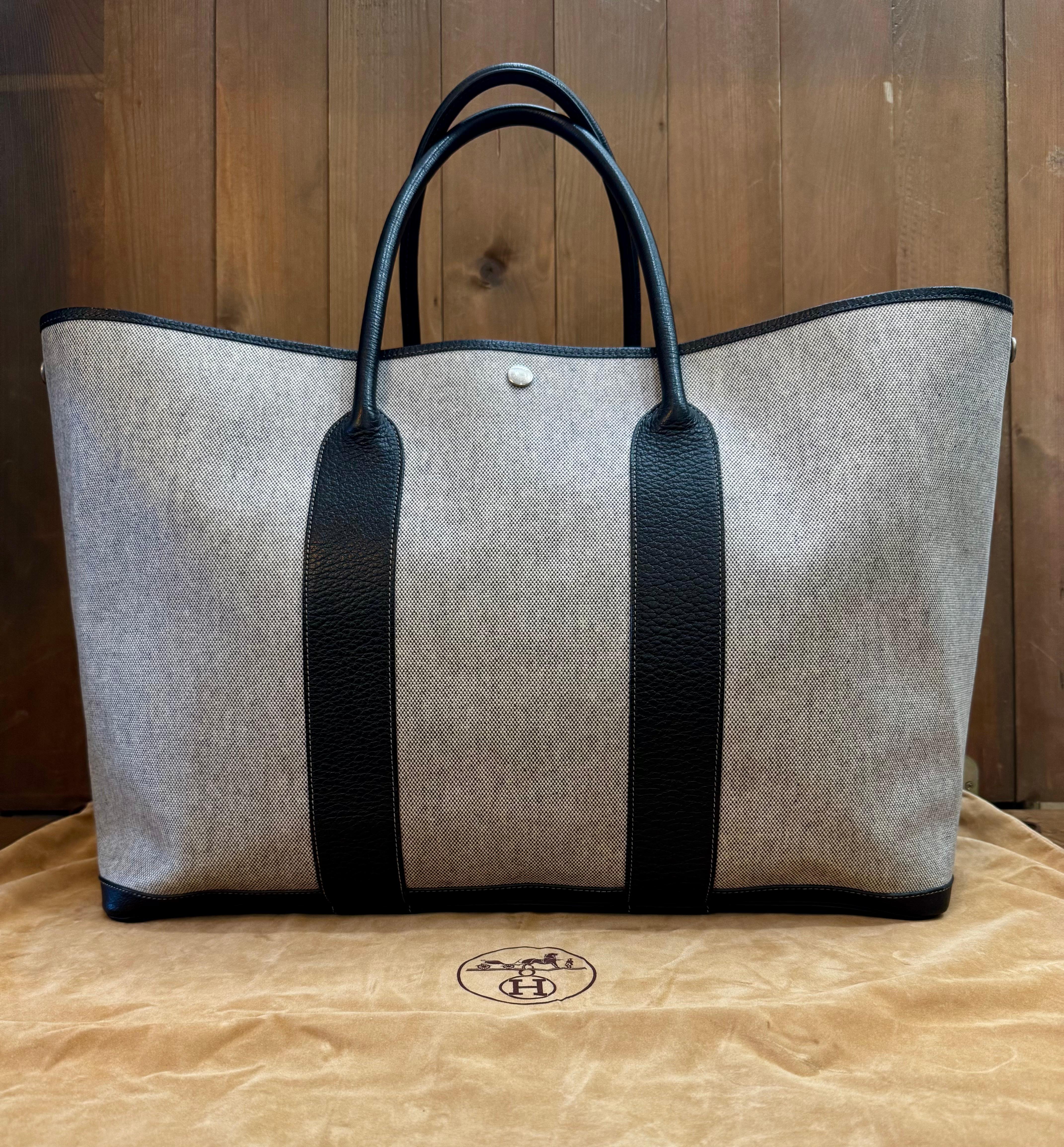 This HERMES Garden Party TGM tote bag is crafted of grey toile canvas trimmed with large-grained calfskin leather in black featuring palladium hardware. Top wide opening with snap fastening opens to a spacious unlined interior. An extra large Hermes
