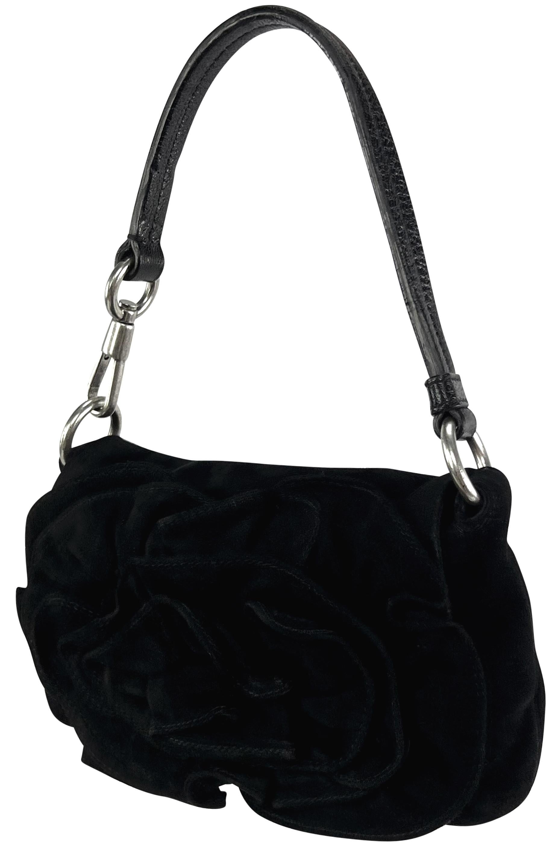 From 2003, Tom Ford designed this black suede Yves Saint Laurent evening bag. Constructed entirely of black suede, this petite bag features silver hardware and a flap design with a bold suede flower accent. 

Approximate Measurements:
Length: