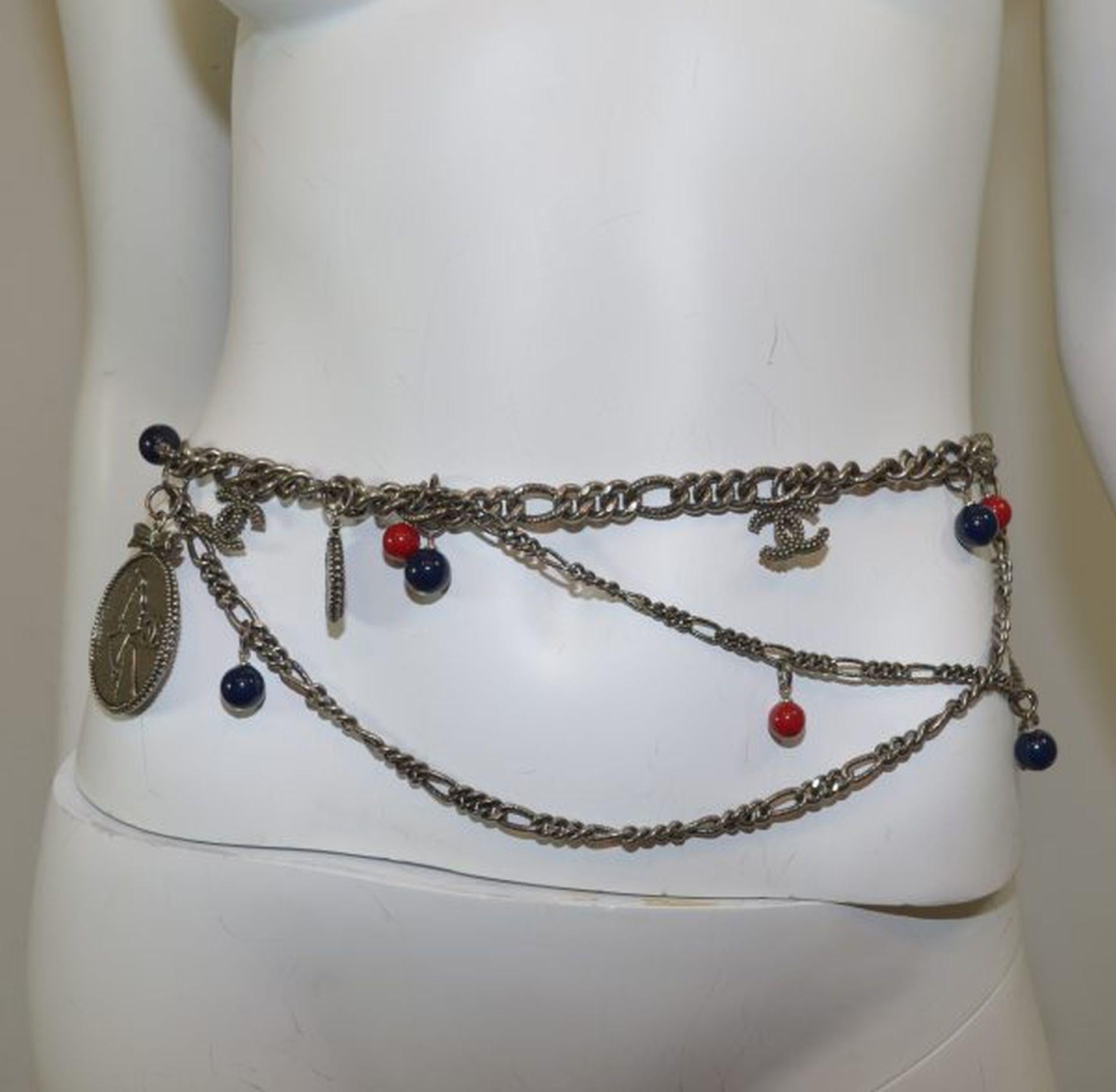 Chanel belt from 2004 Autumn Collection featured in pewter-tone hardware with assorted Coco Chanel silhouette and quote charms, adorned with red and navy blue beads, and signature CC logo charms. Belt is made in France. Excellent
