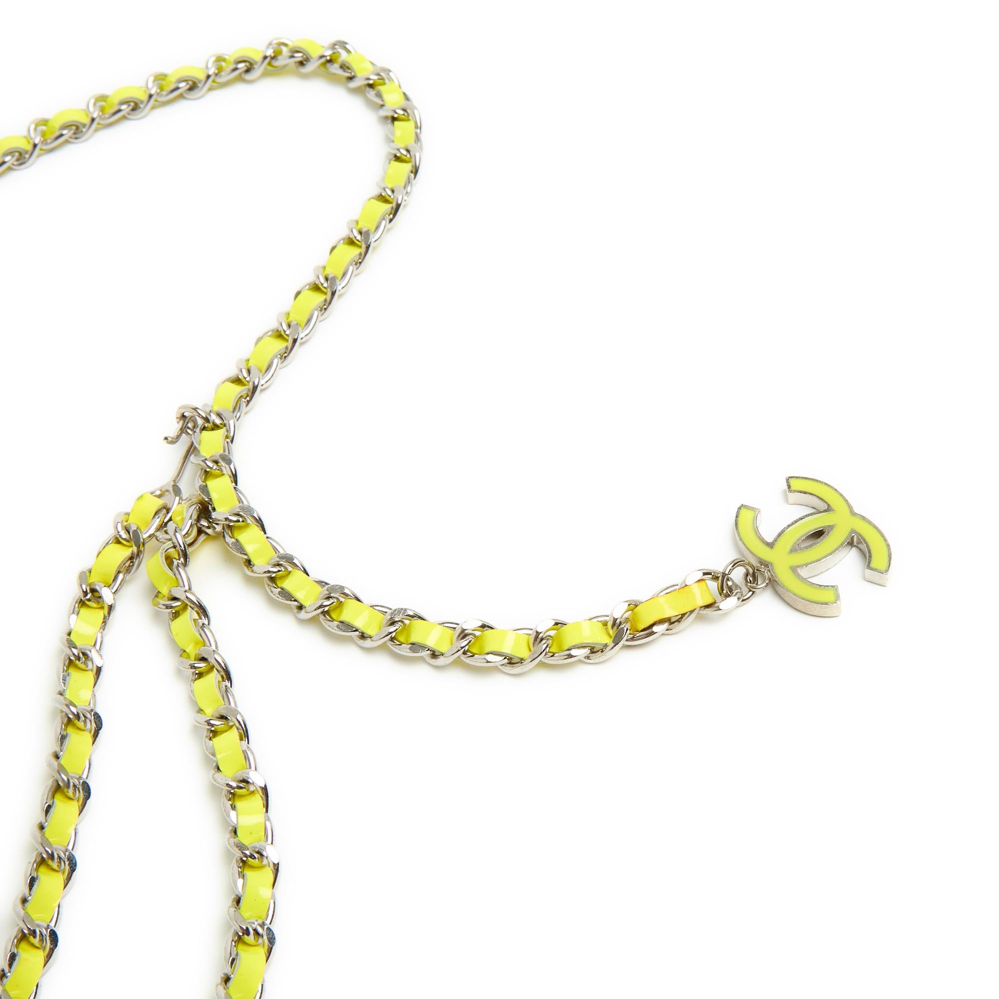 Chanel belt in silver metal chain (ruthenium) interwoven with fluorescent yellow patent leather, 2 chains in front, closed with a hook on a ring or in the chain, end decorated with a large CC in metal and coordinated enamel. Total length of the belt