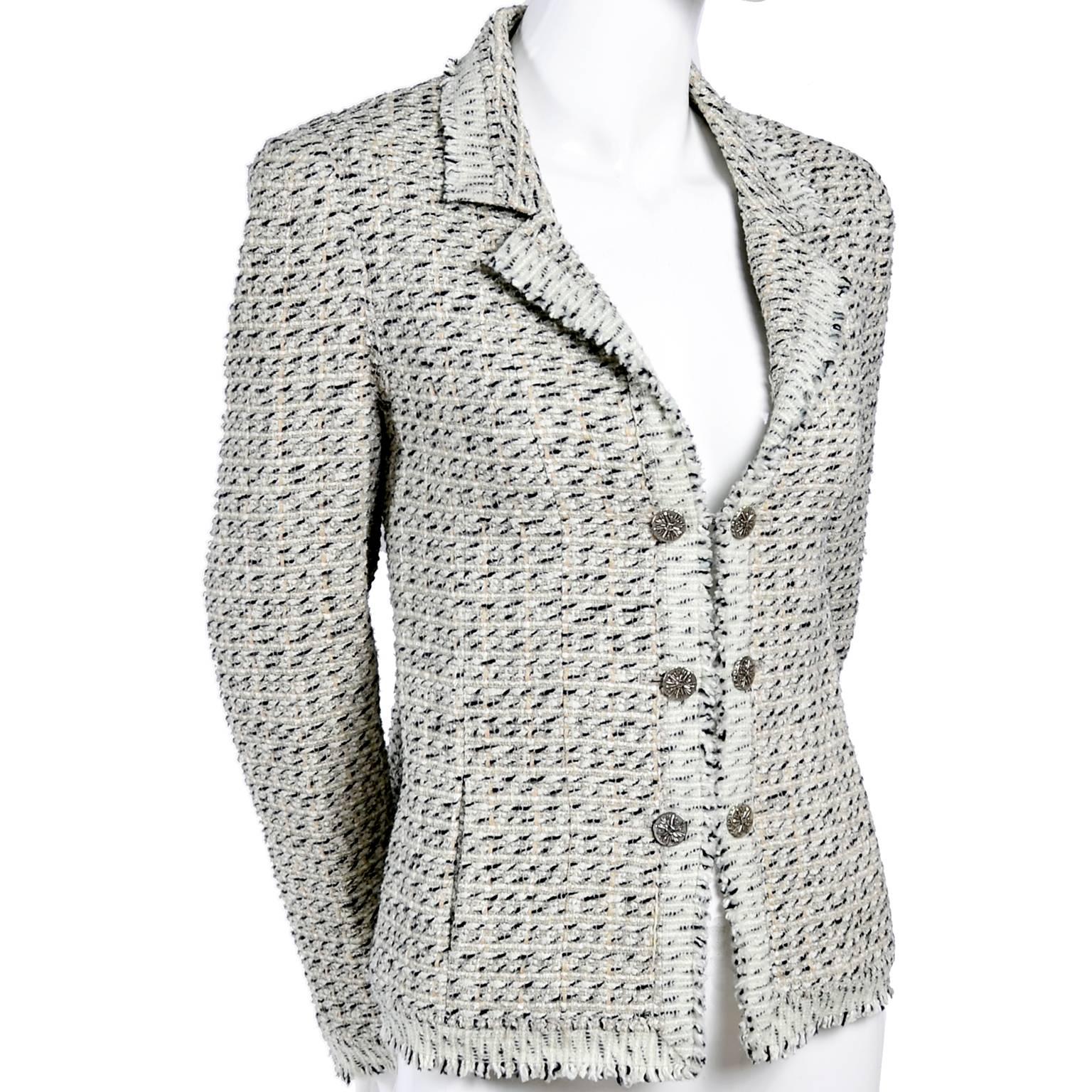This Chanel jacket is from 2004 and is in a black, ivory and cream Lessage fantasy tweed made of 49% cotton 25% wool 11% nylon 10% Rayon and 5% linen. This short blazer has logo pale ecru silk lining, slit pockets, double chain front cc logo buttons