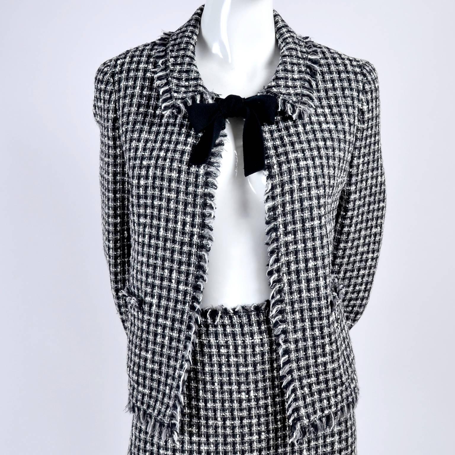 This stylish black and white woven Lesage tweed Chanel Autumn/Winter 2004 collection skirt suit is incredible. The jacket is open in front, tying at the neck with thick black fabric ties, and the two arm cuffs are elastic, with decorative black bows