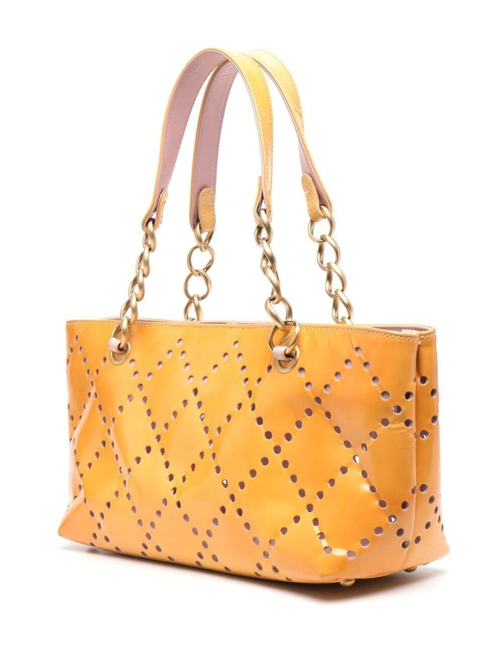 Chanel yellow banana leather tote bag featuring a perforated patent leather pattern, a front logo pattern, gold-tone hardware, an inside pink leather lining, a snap opening, an inside pocket, two leather and chain-link shoulder straps, signature
