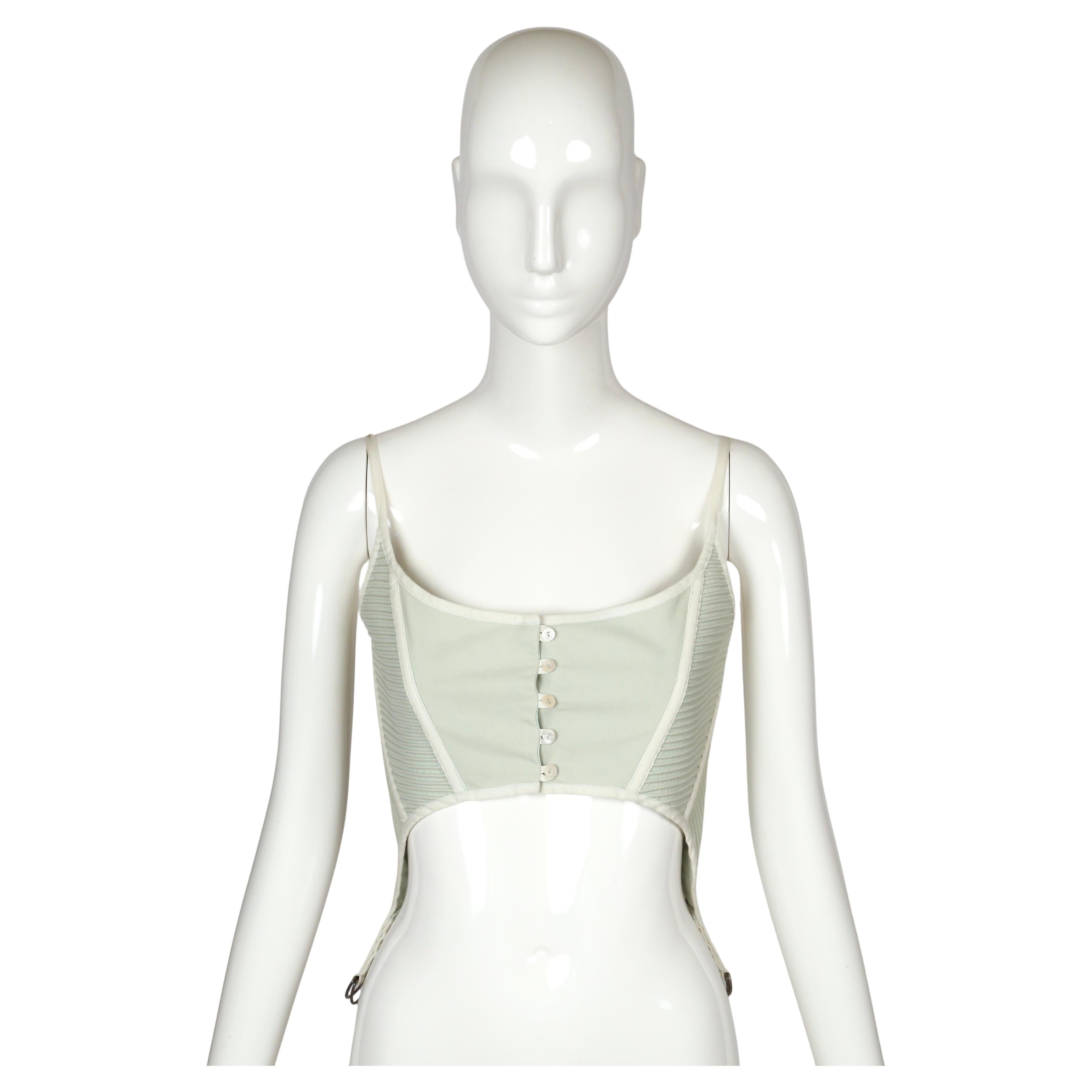 Questo bustier di Alexander McQueen della sfilata primavera/estate 2005 ha un mix perfetto di morbidezza e struttura. È realizzata in cotone color menta chiaro con spalline sottili in cotone, pannelli laterali a coste e bottoncini con motivo