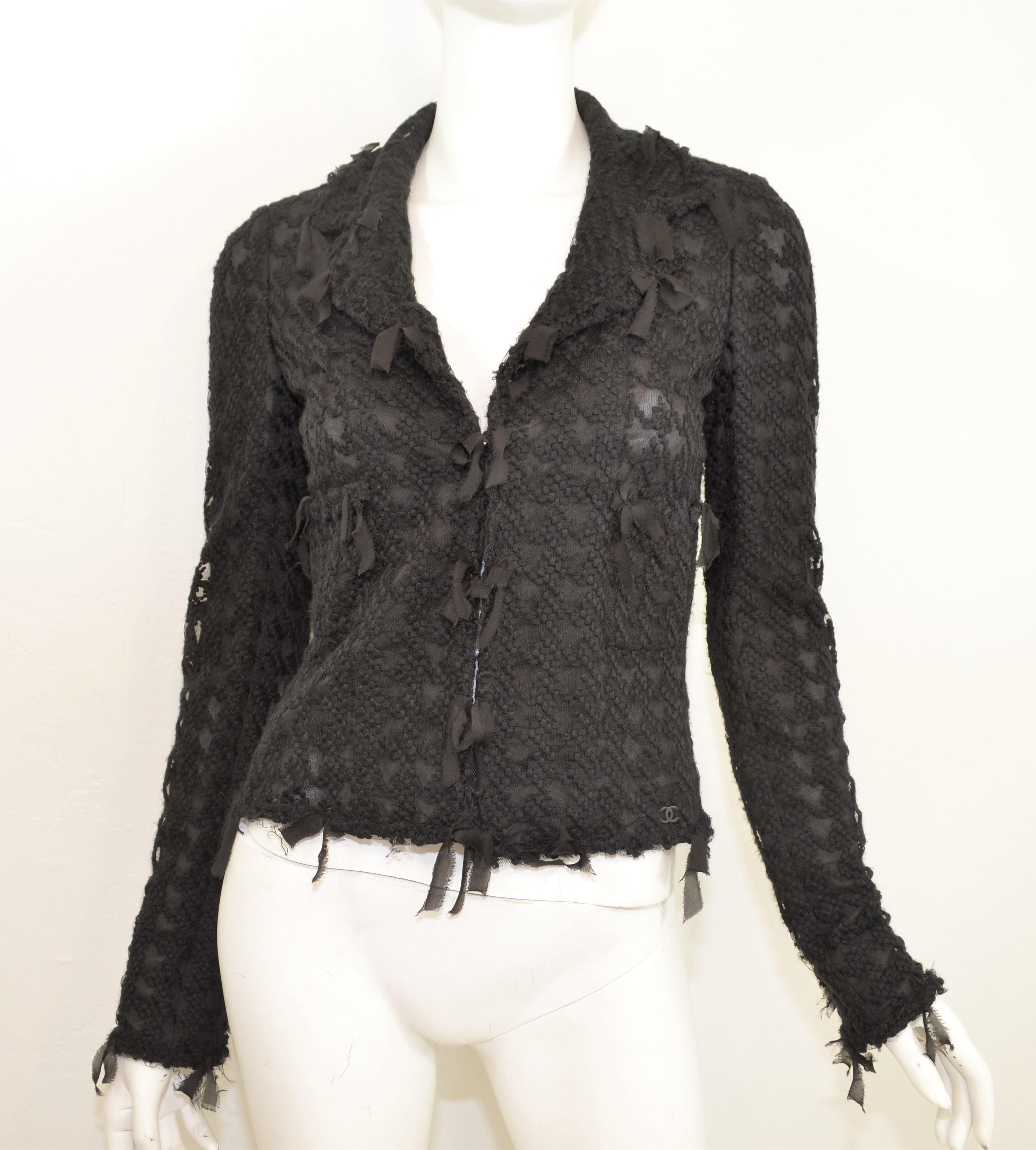 From the 2005 Cruise collection, this Chanel jacket is featured in black with a houndstooth pattern throughout the mesh fabric and a deconstructed silk fringe trimming. Jacket has an open front, camellia flower buttons at the cuffs, a full lining,