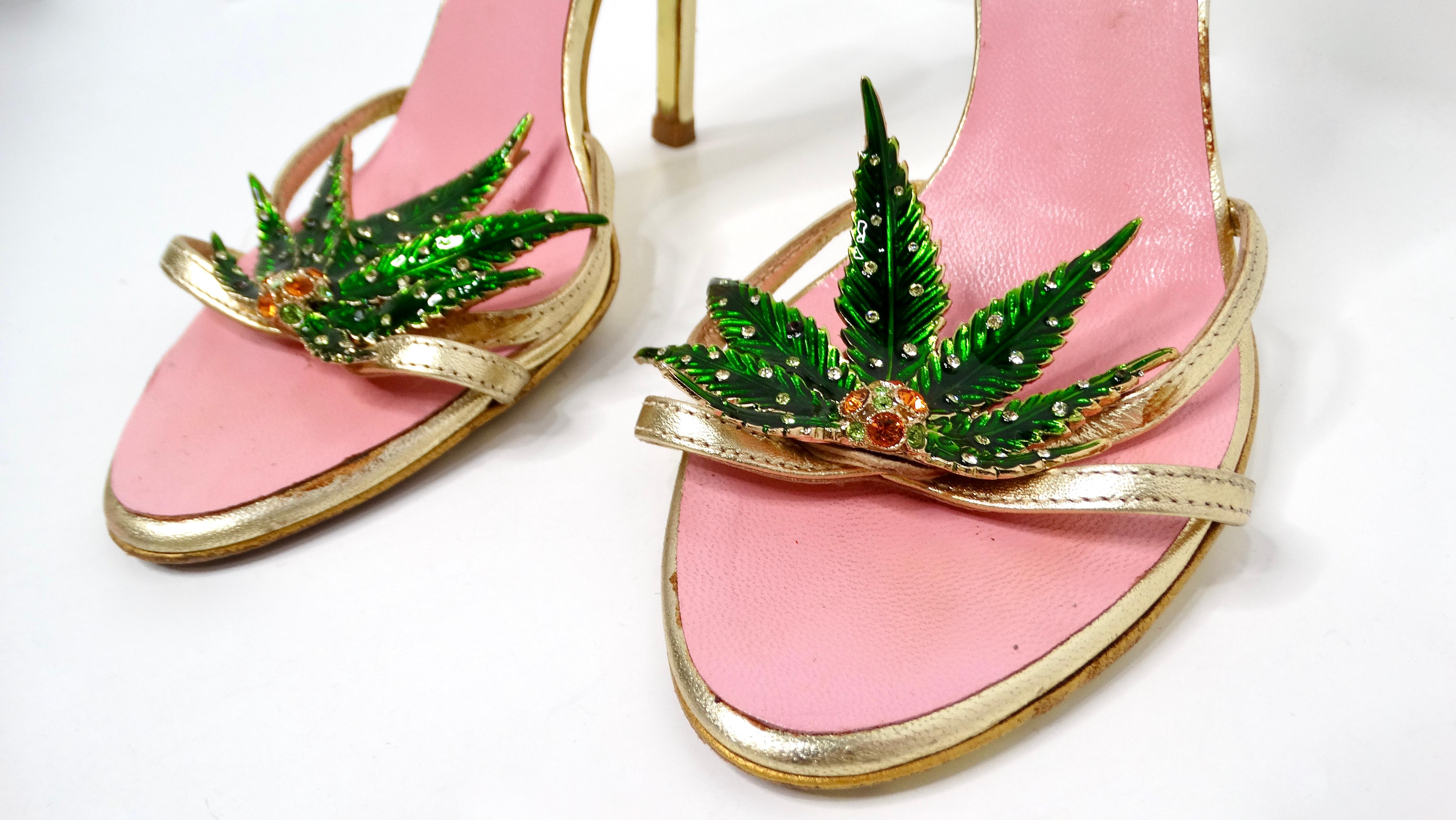The 2005 Dsquared2 Marijuana Leaf Metallic Gold Sandal Heels are a statement piece exuding bold glamour. Crafted from gold metallic leather, these heels feature a vibrant pink sole, offering a playful contrast. The focal point is the green marijuana
