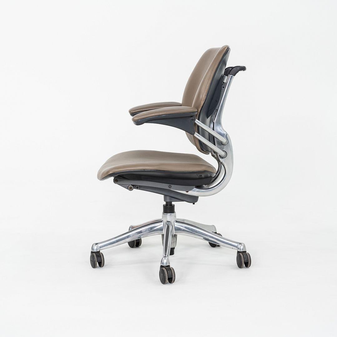 These are Freedom Task Desk Chairs, originally designed by Niels Diffrient in 1999. These particular examples were produced by Humanscale in the USA in 2005. The chairs features an aluminum 5-star base and are upholstered in a dark tan leather. The