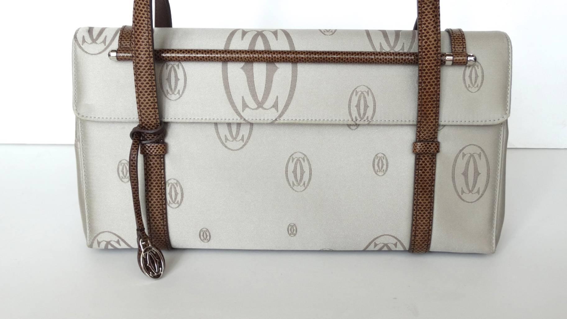 The most adorable Cartier top handle bag from their 2006 Happy Birthday collection! Made of a cool grey satin fabric printed all over with dark grey Cartier logos. Contrasted with brown leather strap and trim. Embellished with a silver Cartier