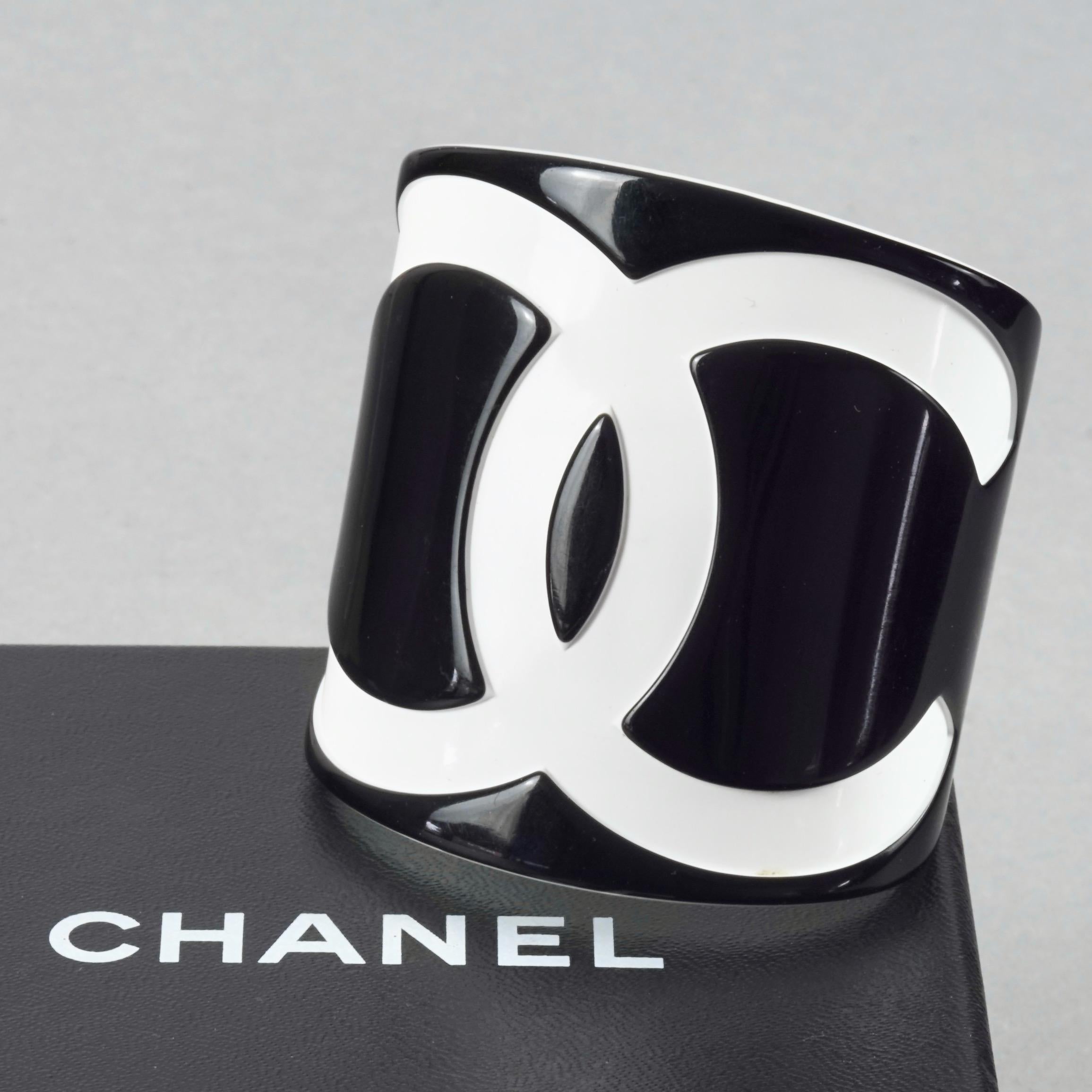 2006 CHANEL CC Logo Black and White Perspex Wide Cuff Bracelet

Measurements:
Height: 2.55 inches (6.5 cm)
Inner Circumference: 5.78 inches (14.7 cm) including opening
Inner Horizontal Diameter: 2.16 inches (5.5 cm)
Inner Vertical Diameter: 1.65
