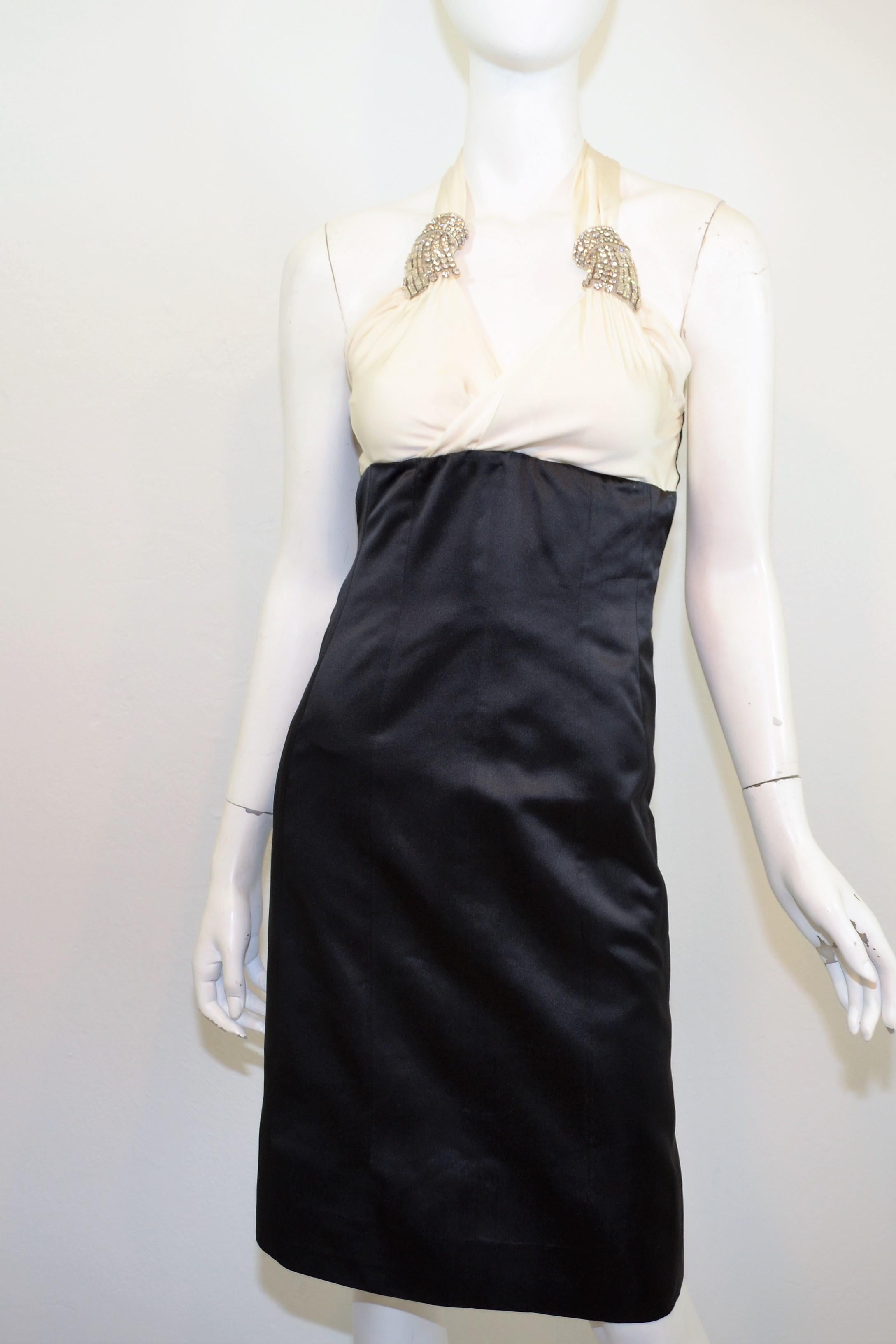 Chanel dress from 2006 A collection featured in a ivory and black satin with rhinestone brooches at the shoulder straps. Dress has a back zipper closure with a CC dangle zipper pull, and a corseted lining. Composed with 100% silk, size 38, made in