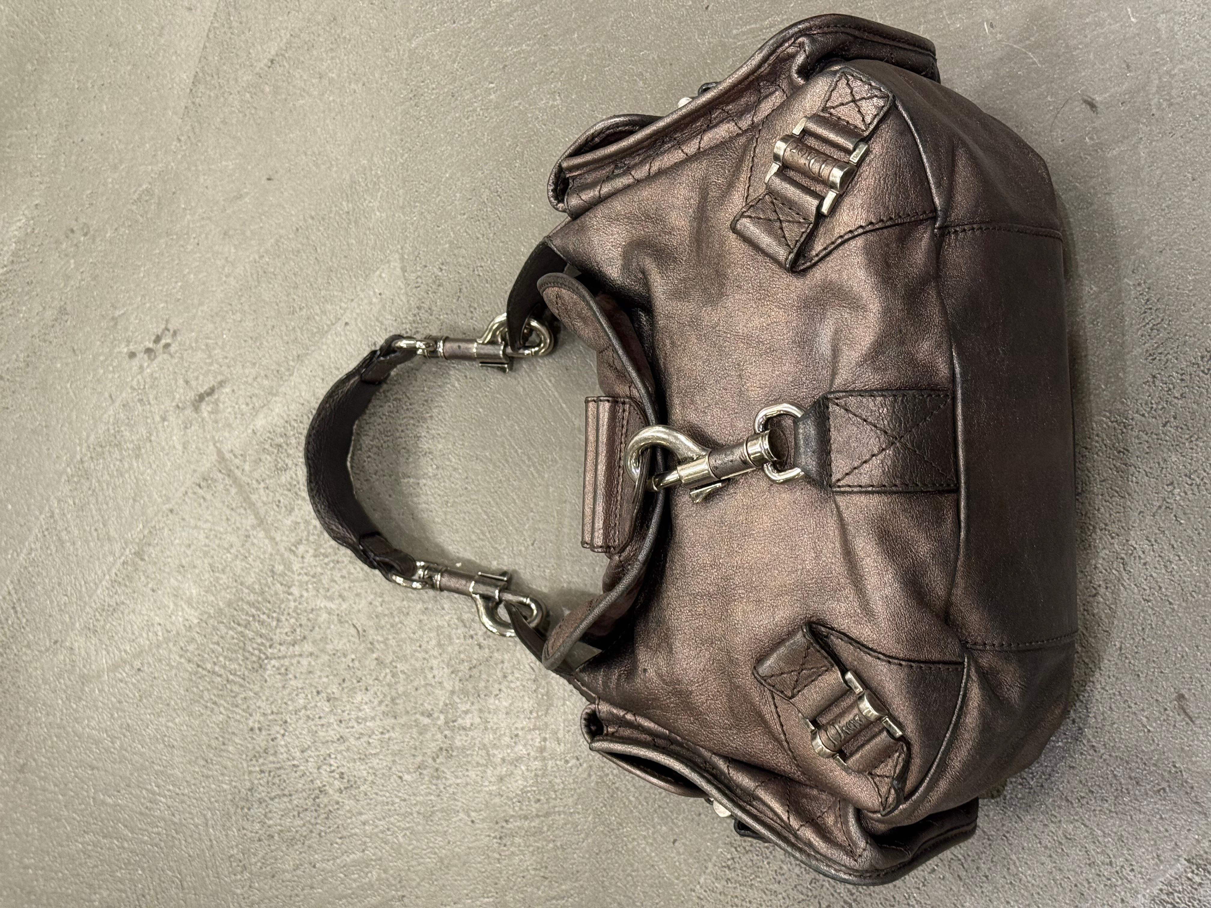 2006 Dior by John Galliano Rebelle Hobo Bag

This 2006 Dior Rebelle hobo bag, designed under John Galliano, embodies the bold, sculptural energy that defined his era at the maison. Crafted in metallic leather with exaggerated folded panels,