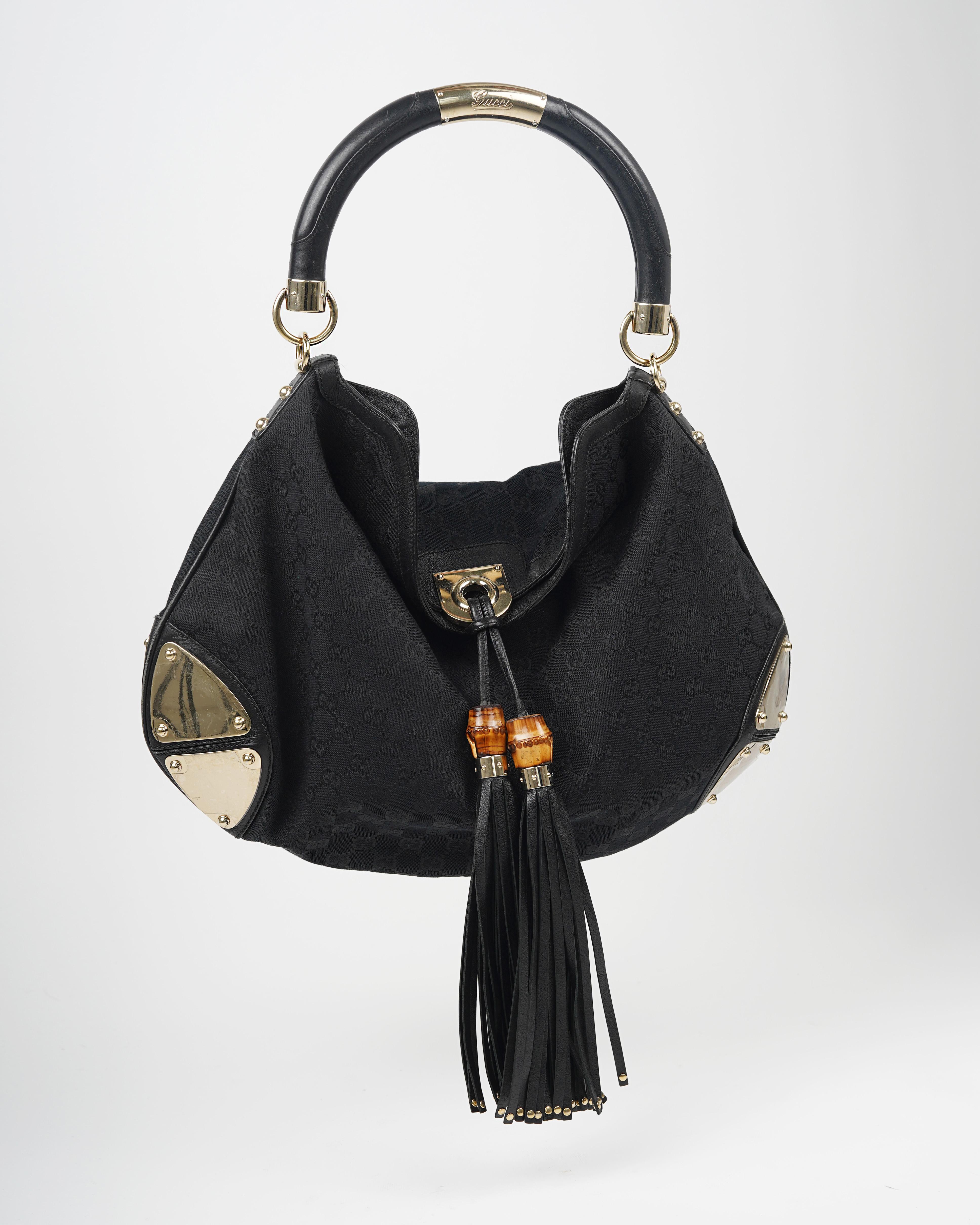 Presenting the Gucci by Frida Giannini black logo canvas Indy bag with gold embellishments and bamboo, leather tassels. 
The Indy was first launched by the Italian fashion house in 2006, under the helm of Frida Giannini. “For me, the Indy bag