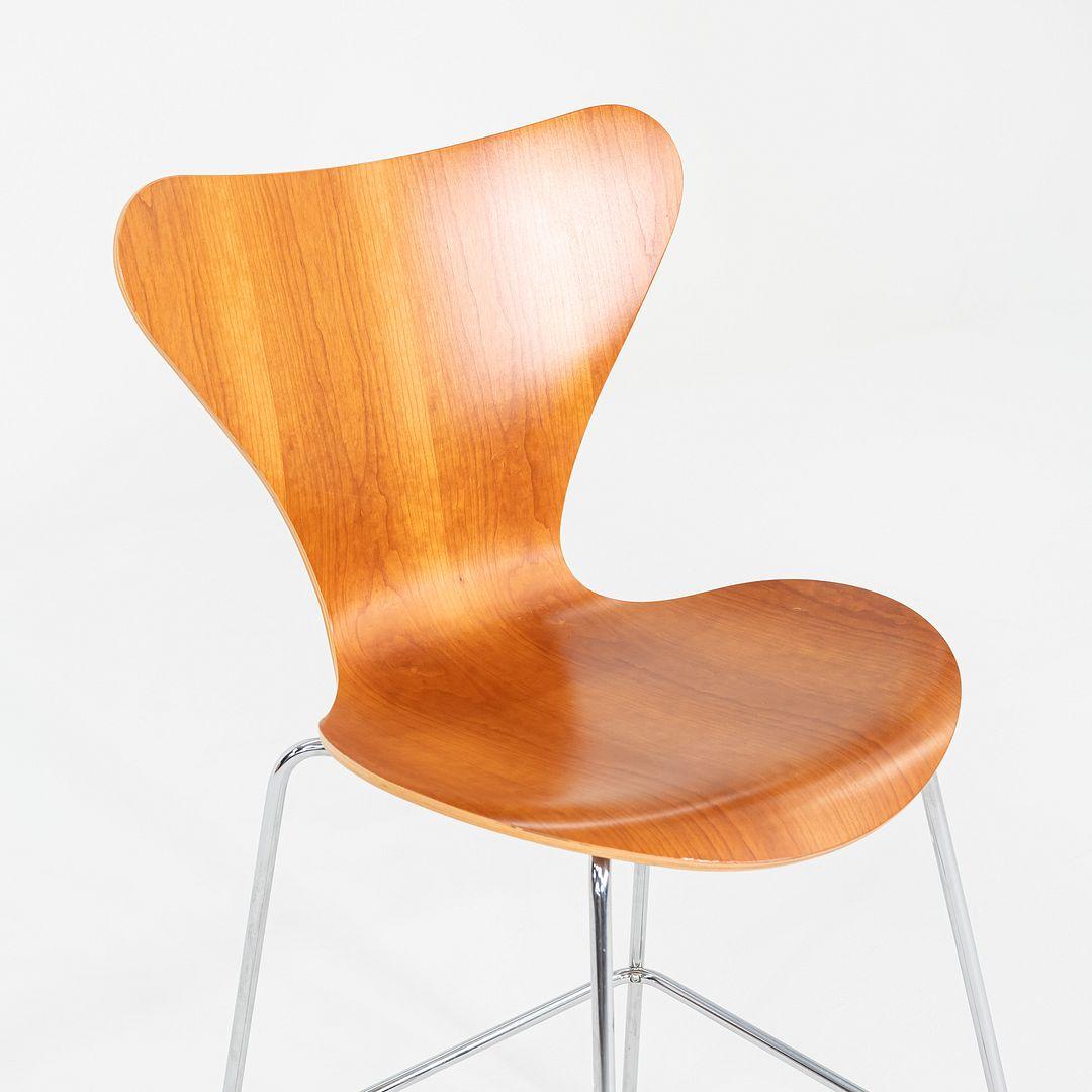 These are Series 7 Counter Stools, originally designed by Arne Jacobsen for Fritz Hansen in 1955. These particular examples date to 2007 and 2008. The stools are comprised of a steel base with a cherry wood seat. The listed price includes one stool