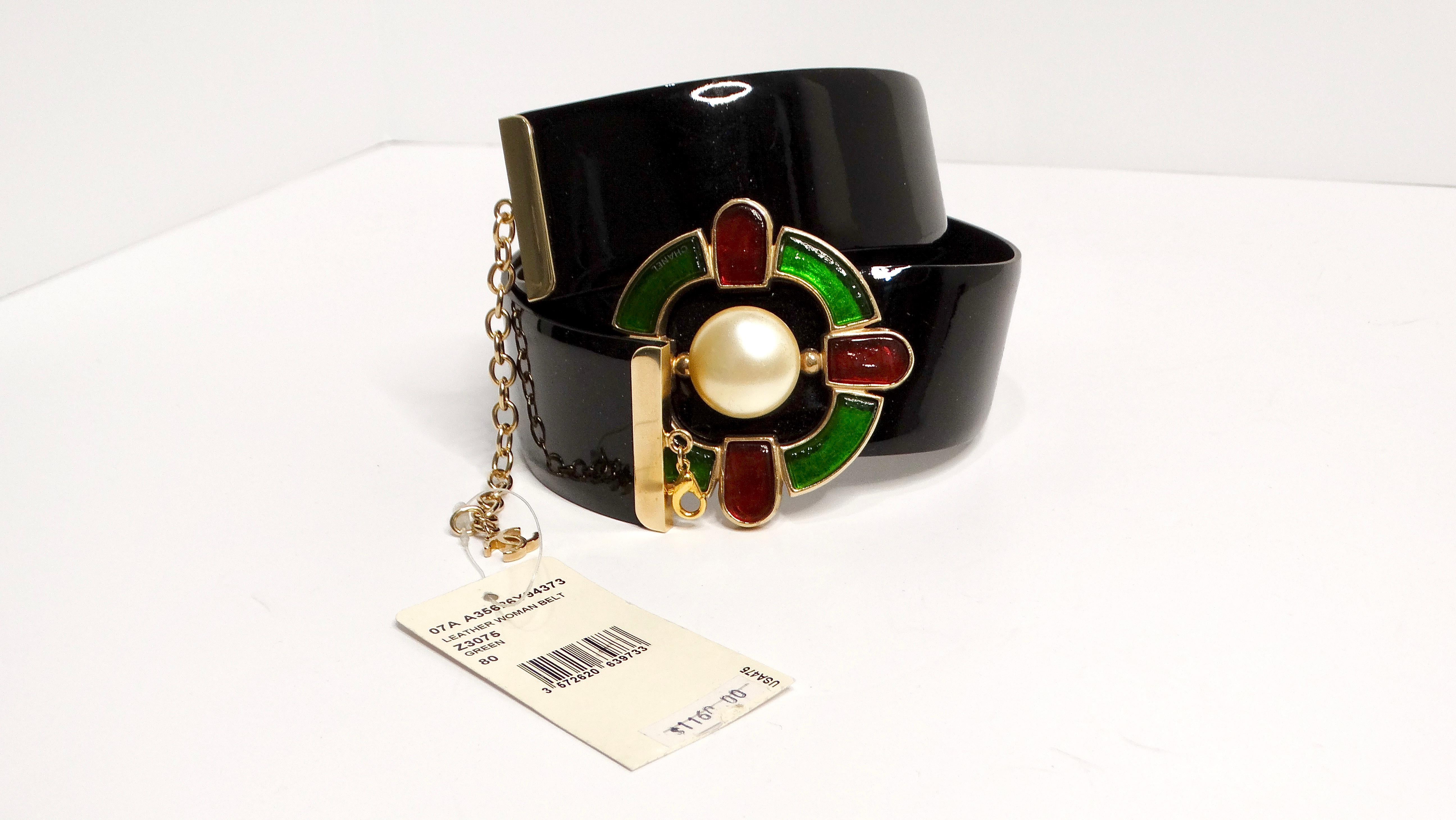 The 2007 Chanel Gripoix Medallion Patent Leather Belt with Pearl is a striking fusion of elegance and edge. The belt features a bold patent leather strap in a classic black, highlighted by a Gripoix medallion in vibrant red and green hues,