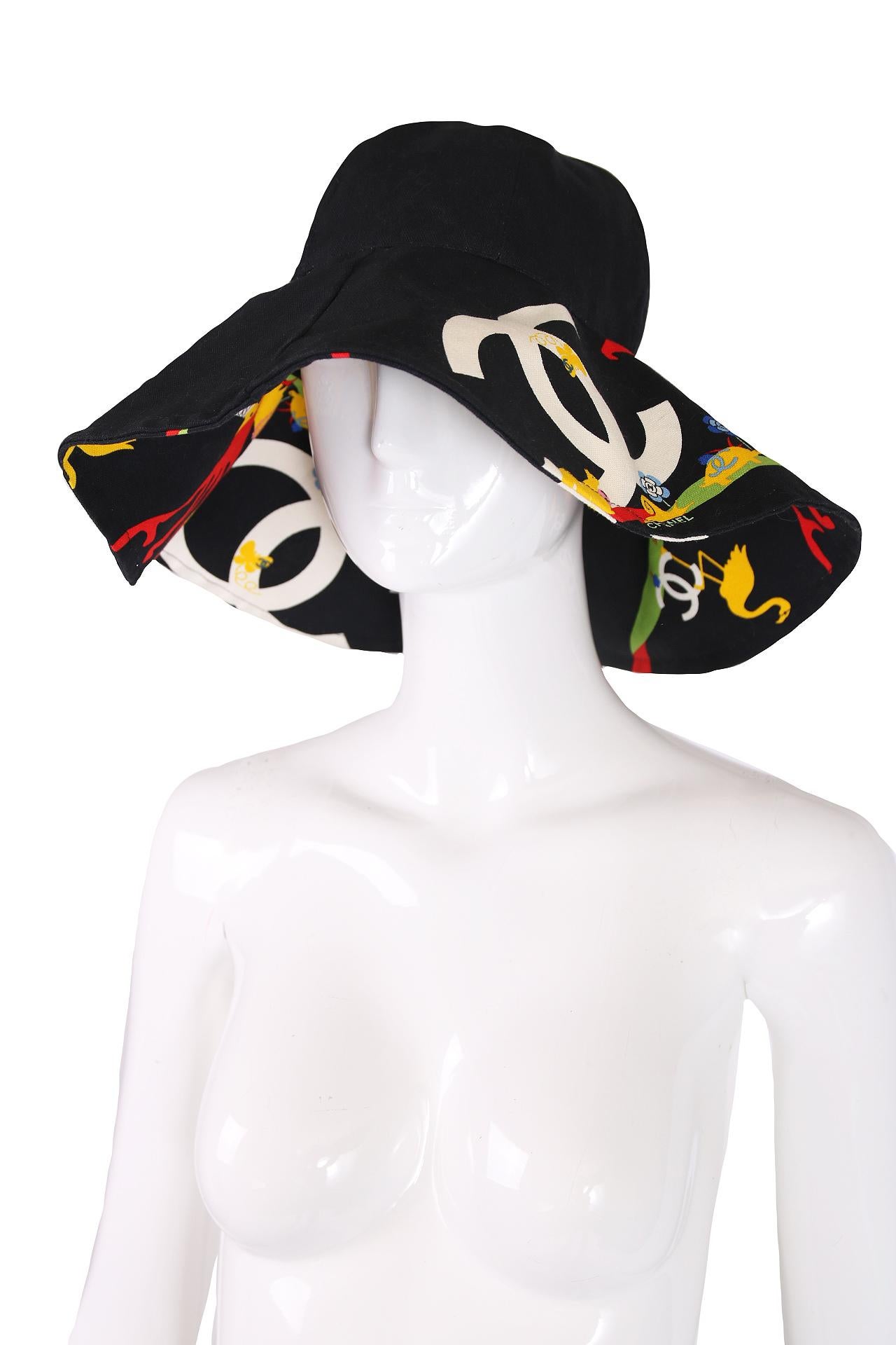 2007 Chanel cotton canvas navy blue floppy wide-brimmed hat with a print featuring a variety of adorable animals wearing the CC logo, flowers with a CC logo center, an owl seated in a red tree and an oversized white CC logo motif in the background.
