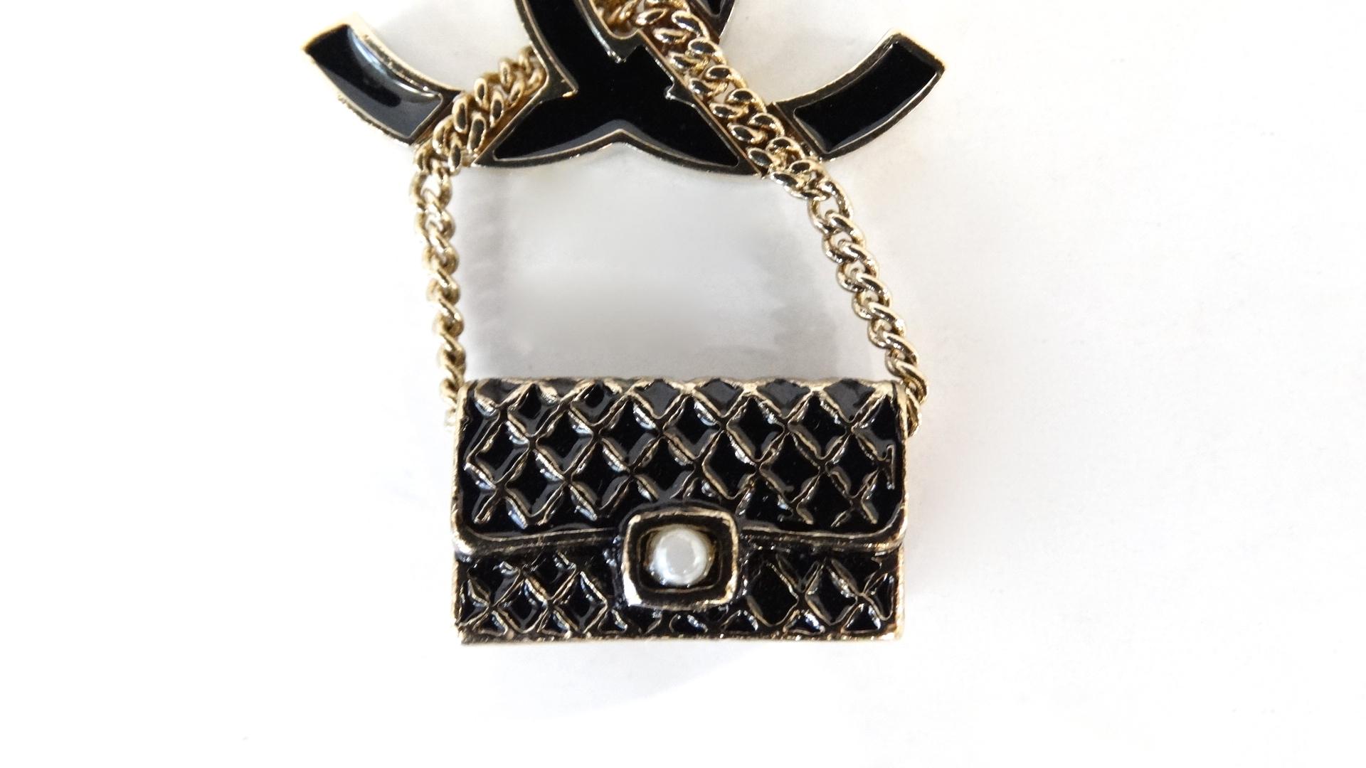 The Most Adorable Accessory Is Here! Circa Spring 2007, this Chanel purse charm features a black enamel Chanel CC with a gold plated trim. Hanging off the CC is the iconic classic 2.55 bag accented with a small faux pearl. The gold toned link chain