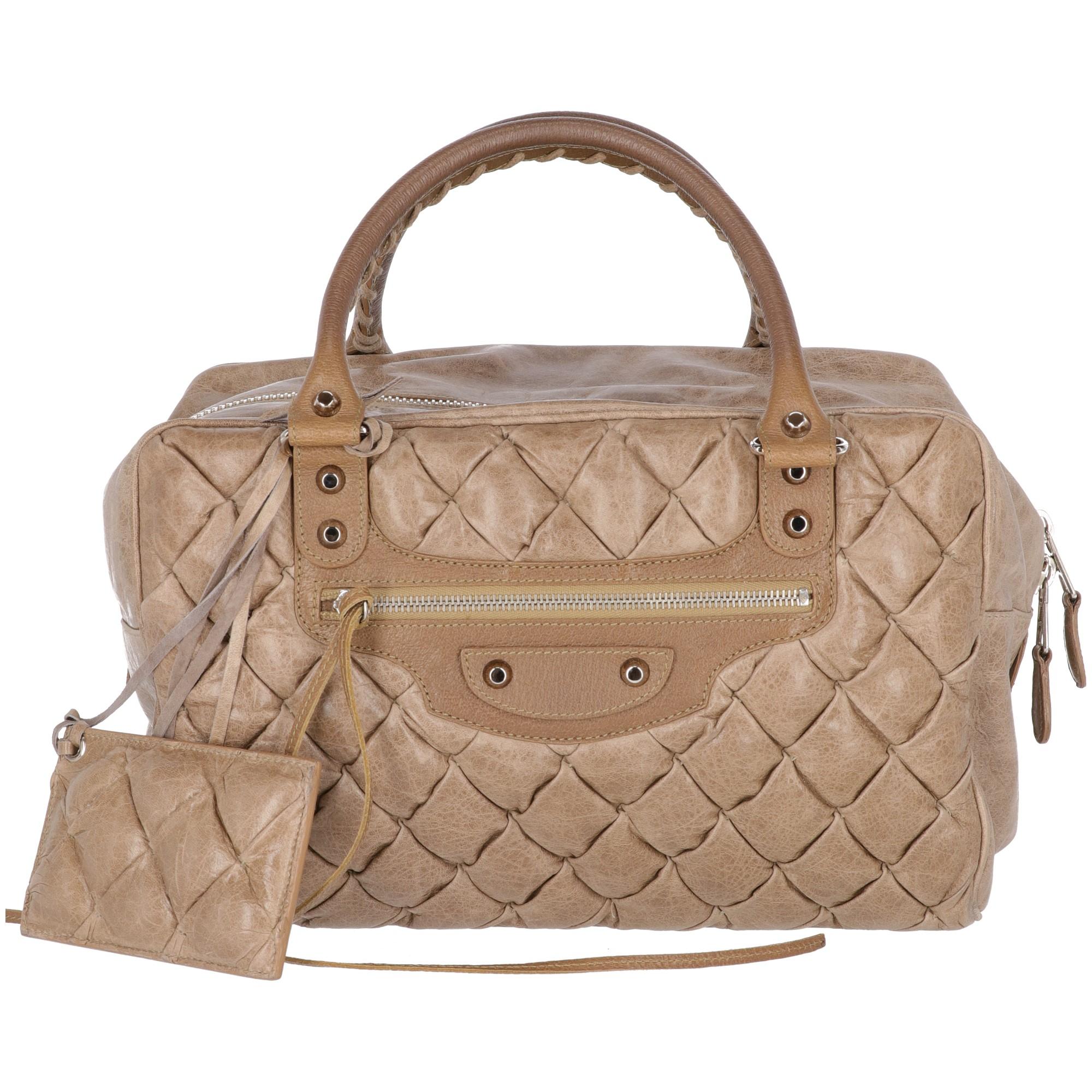 The stylish Balenciaga Motorcycle turtle dove colored real leather quilted handbag features a silver-tone metal zip fastening, a decorative zip with studs on the front and two handles with braided leather strings and silver metal buckles. The lining