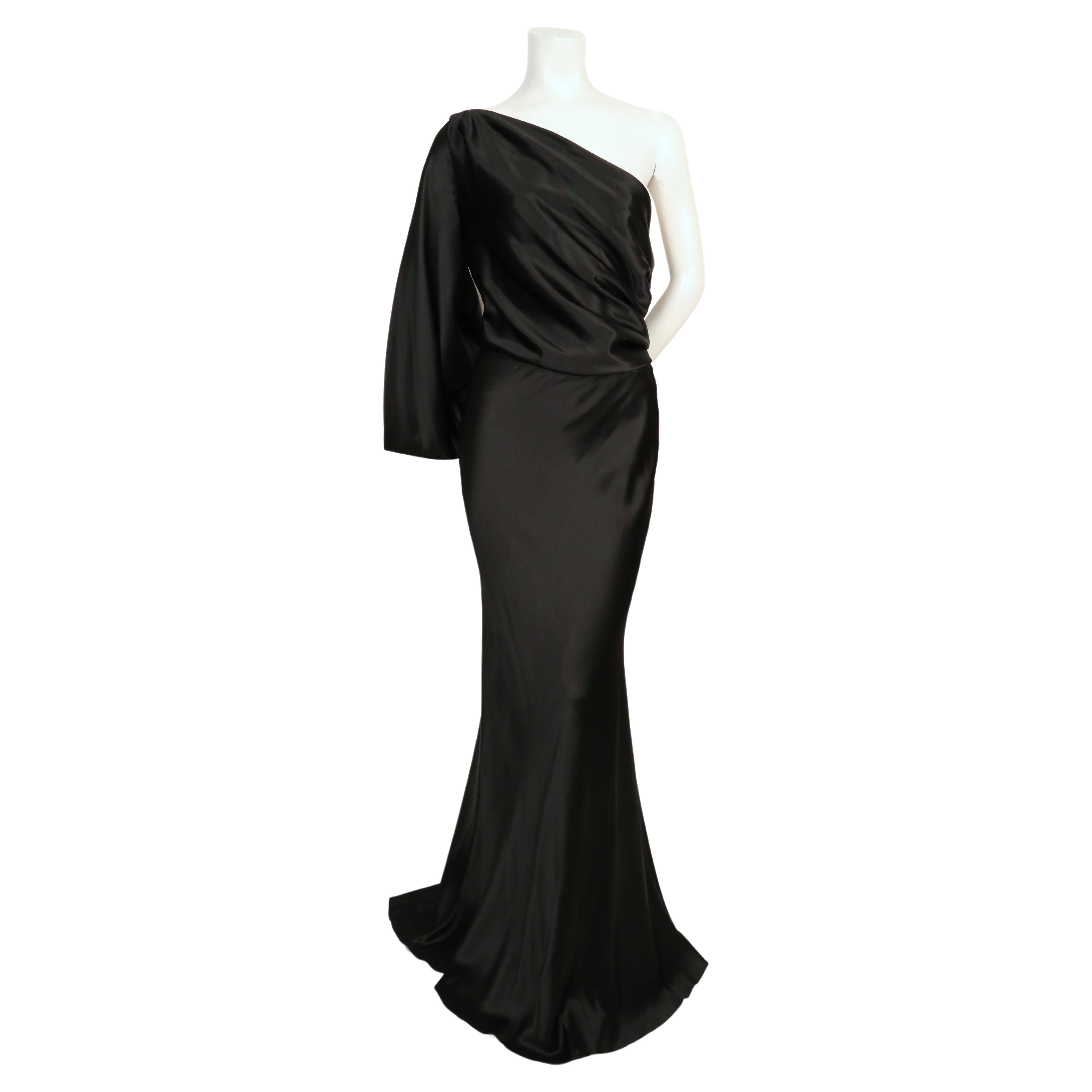 Jet-black, bias-cut jersey gown with asymmetrical one sleeve designed by Alexander McQueen dating to fall 2008. Dress has beautifully draped arm with small covered button closure at wrist. Dress is labeled an Italian size 40, however it best fits a