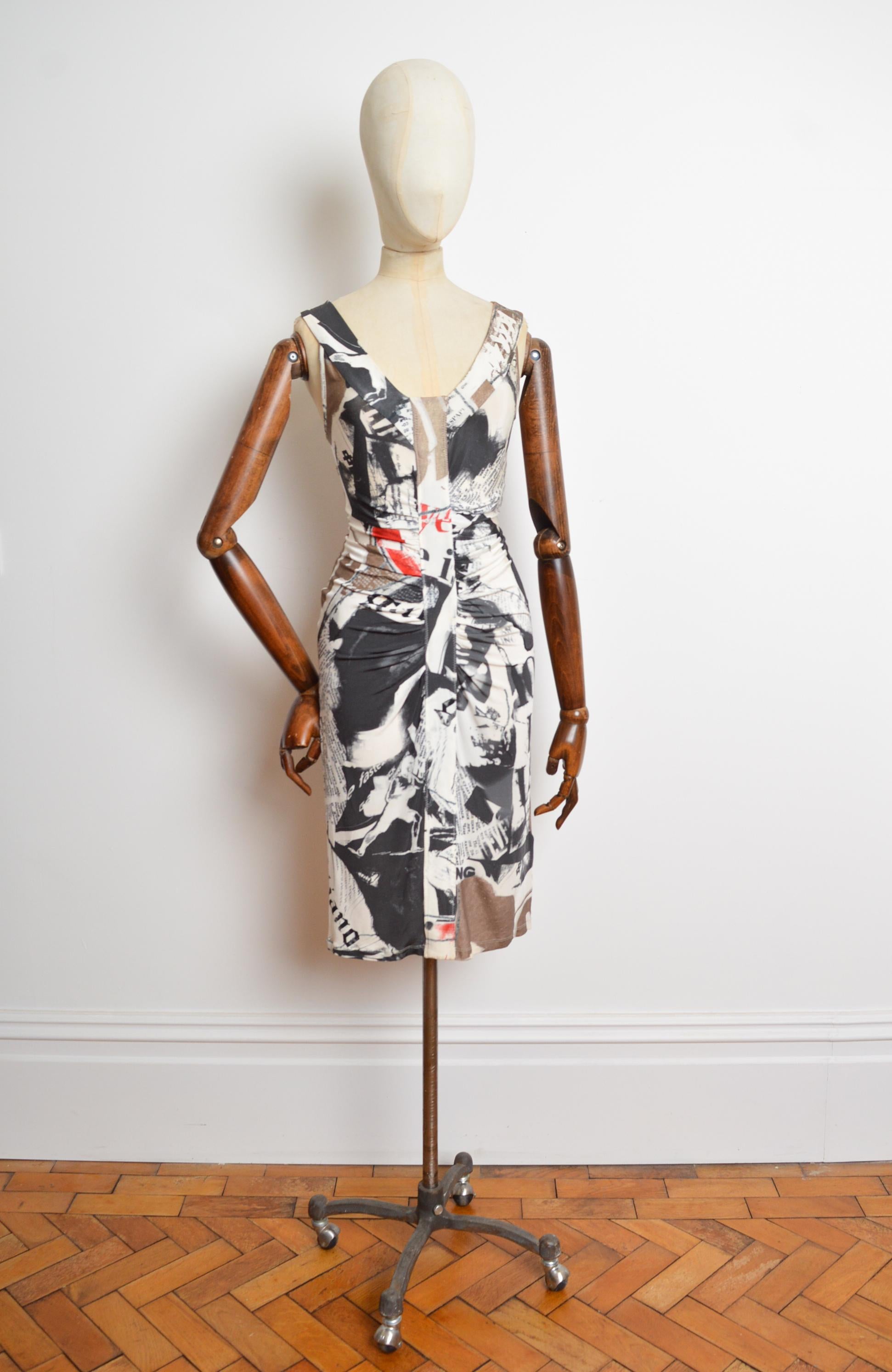 A Fabulous 2000's John Galliano newspaper print dress, featuring rouche, draped panel detail down the front to provide an hour glass silhouette and just to the knee-length hem. 
Size; U.K. 10-12
Measurements are provided in inches (‘’)
Pit to Pit;