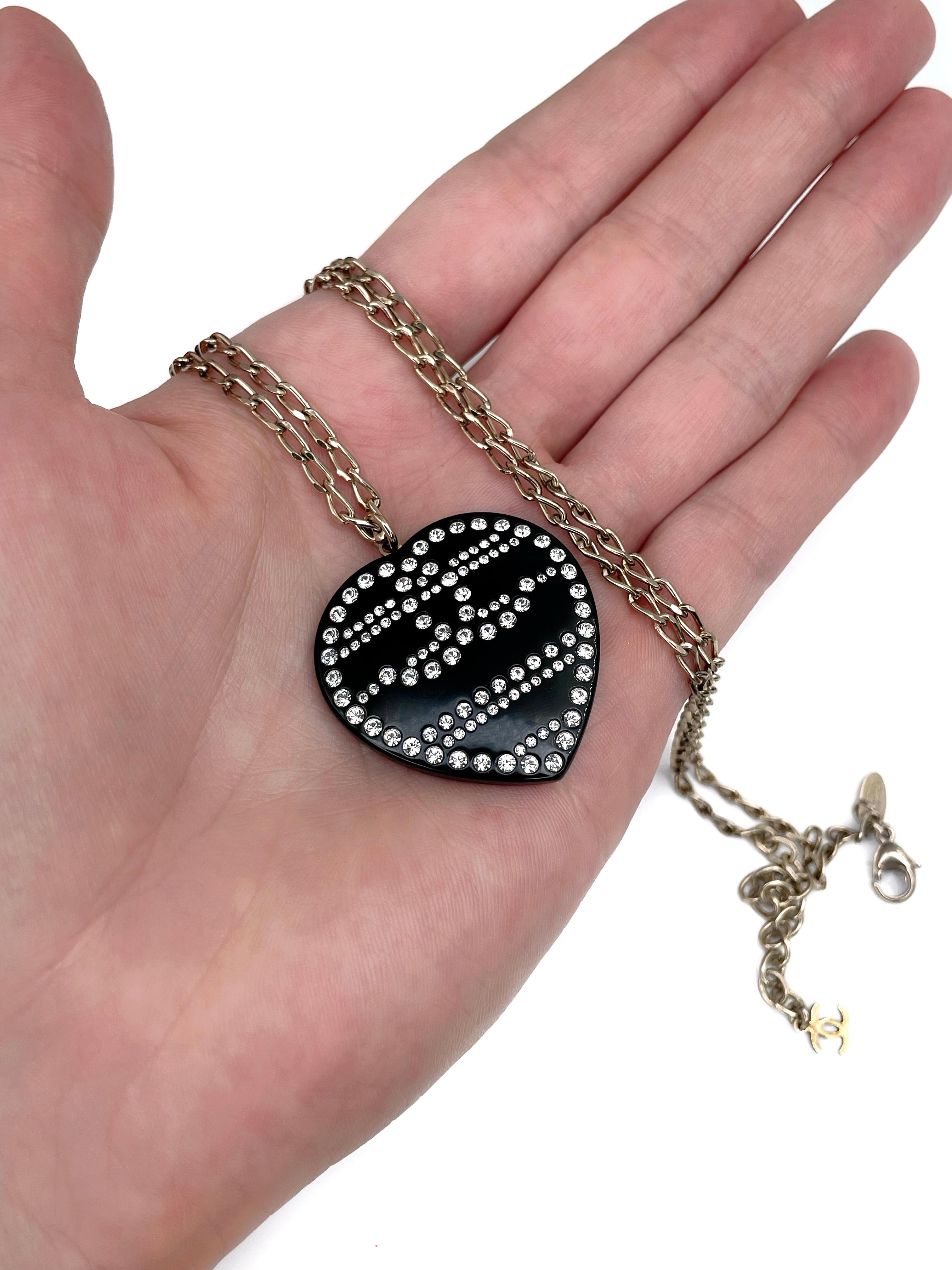 This is a heart pendant with a chain designed by Chanel in 2009. The piece is gold plated. It is crafted in black resin and is adorned with clear shiny crystals. 

Chain can be worn in different lengths - from 65cm (at max) to 60cm (at min).