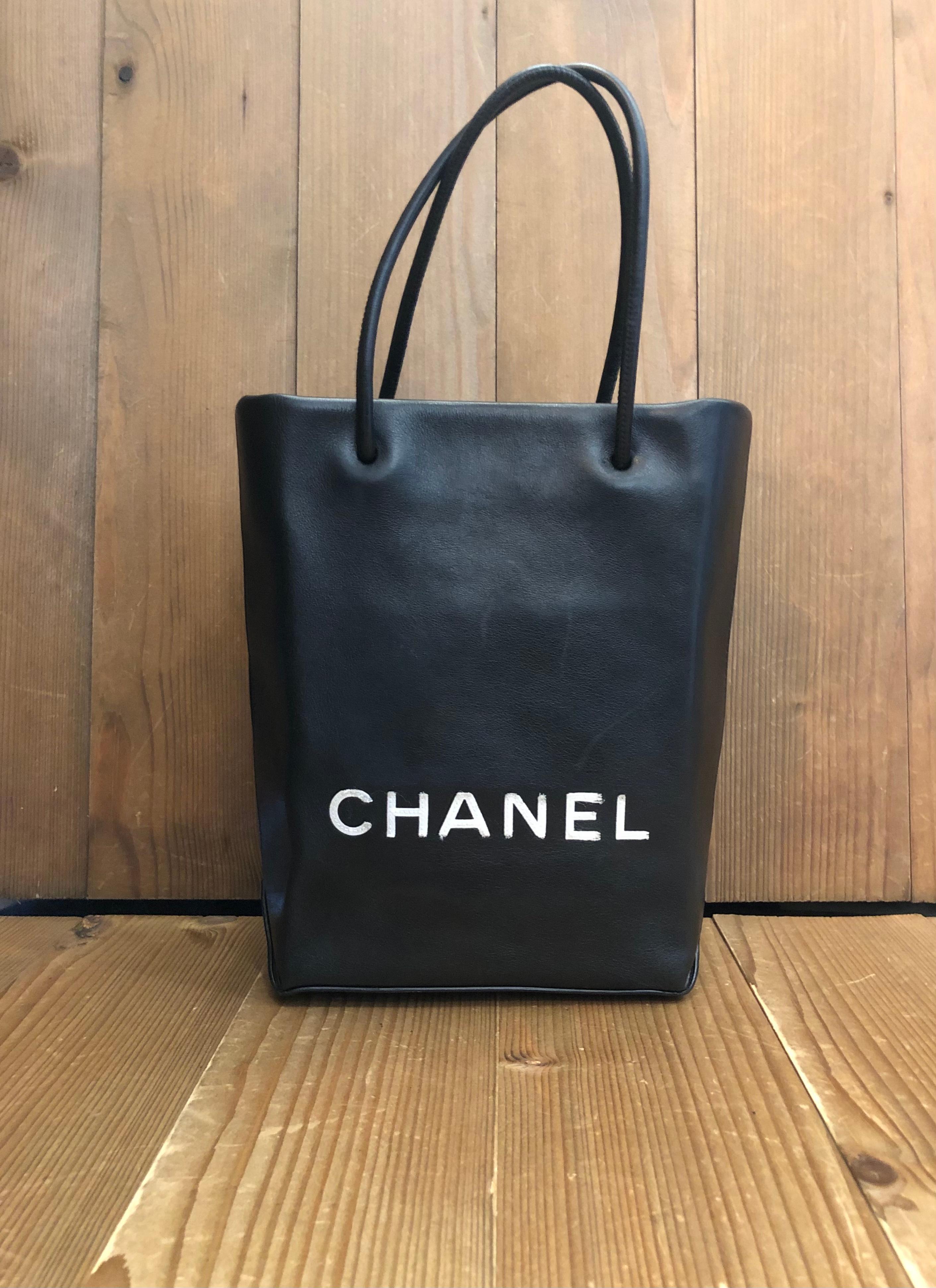 This stylish Chanel mini shopper tote bag is crafted of calfskin leather in black with letters CHANEL in white fabric sewn on the front. Karl Lagerfeld once admitted to collecting chic paper bags which made him decide to immortalize the iconic paper