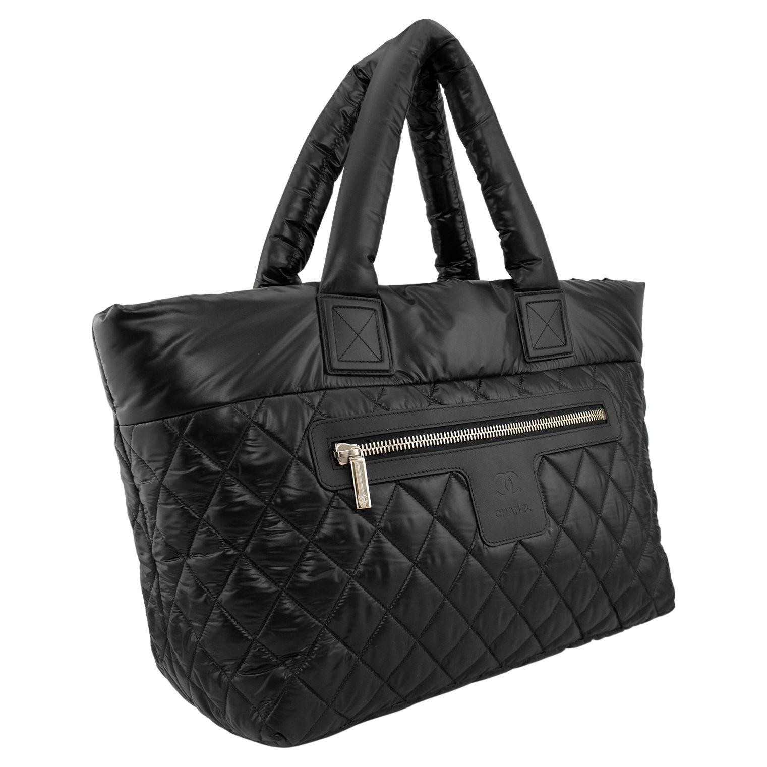 Chanel Coco Cocoon Medium tote quilted in black lined with burgundy nylon. Features padded top handles, exterior zip pocket, and silver-tone hardware. Opens with a zip closure, nylon interior with a zip pocket. In excellent unused condition.