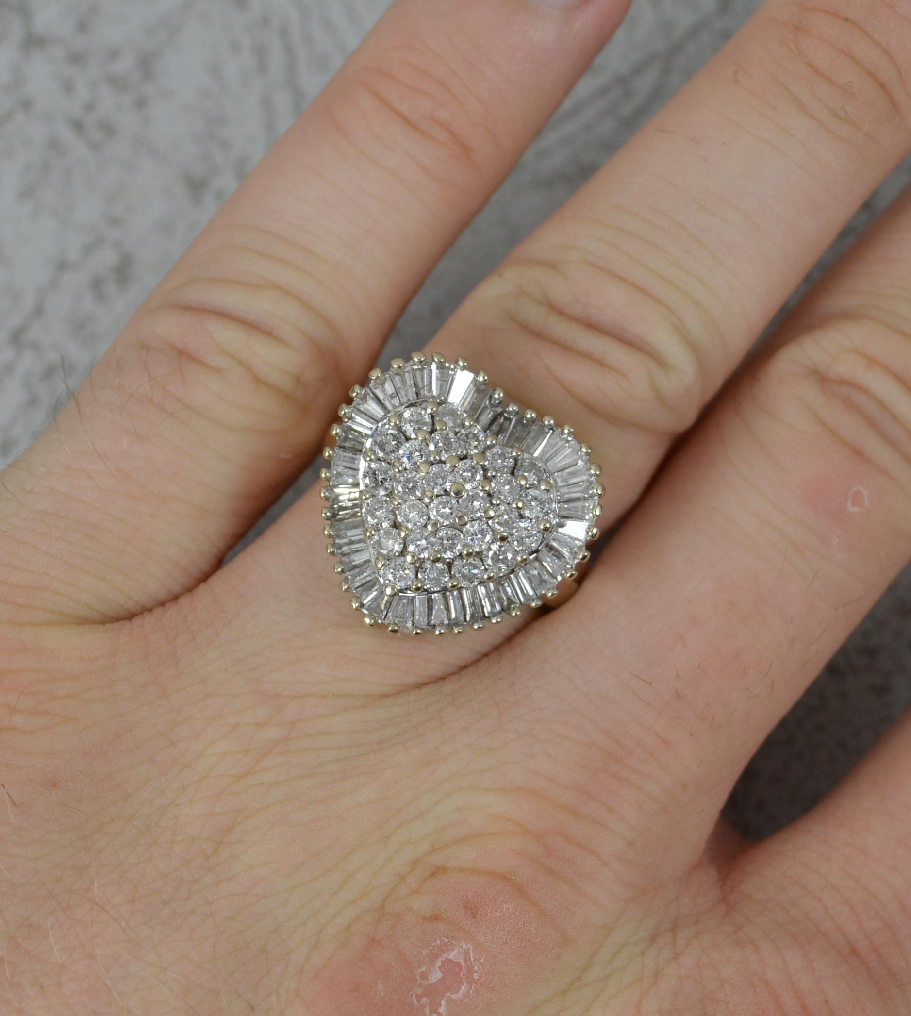 Ein hervorragender zeitgenössischer Diamant-Cluster-Ring.
Massive 18 Karat Weißgold Beispiel.
Der herzförmige Clusterkopf ist mit drei Lagen runder Diamanten im Brillantschliff und einer abschließenden Einfassung aus Diamanten im Baguetteschliff