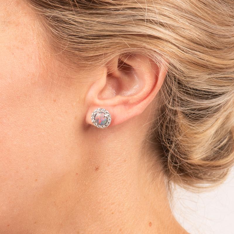 These beautiful stud earrings feature 2.00ctw of natural oval opals surrounded by a halo of .86ctw diamonds. These are set in 18 karat white gold and have a friction post back. Each opal is sourced from the Lightning Ridge area of Australia and is