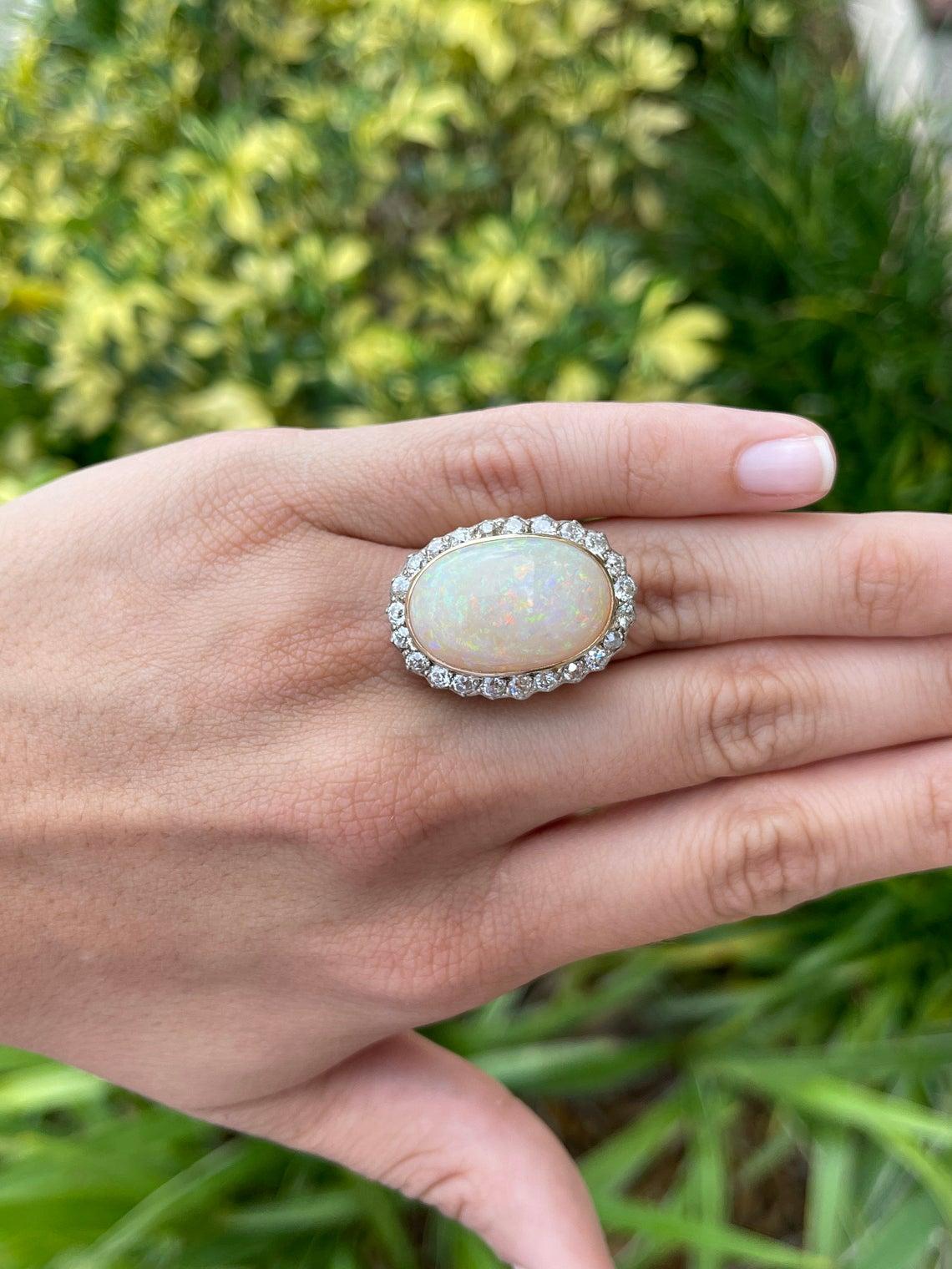 Featured here is a handmade, antique victorian opal and diamond statement ring. This grand piece is impressive and it is sure to get noticed. The center holds a natural white opal that contains fire and life. The large 20.0ct opal is a bezel set in