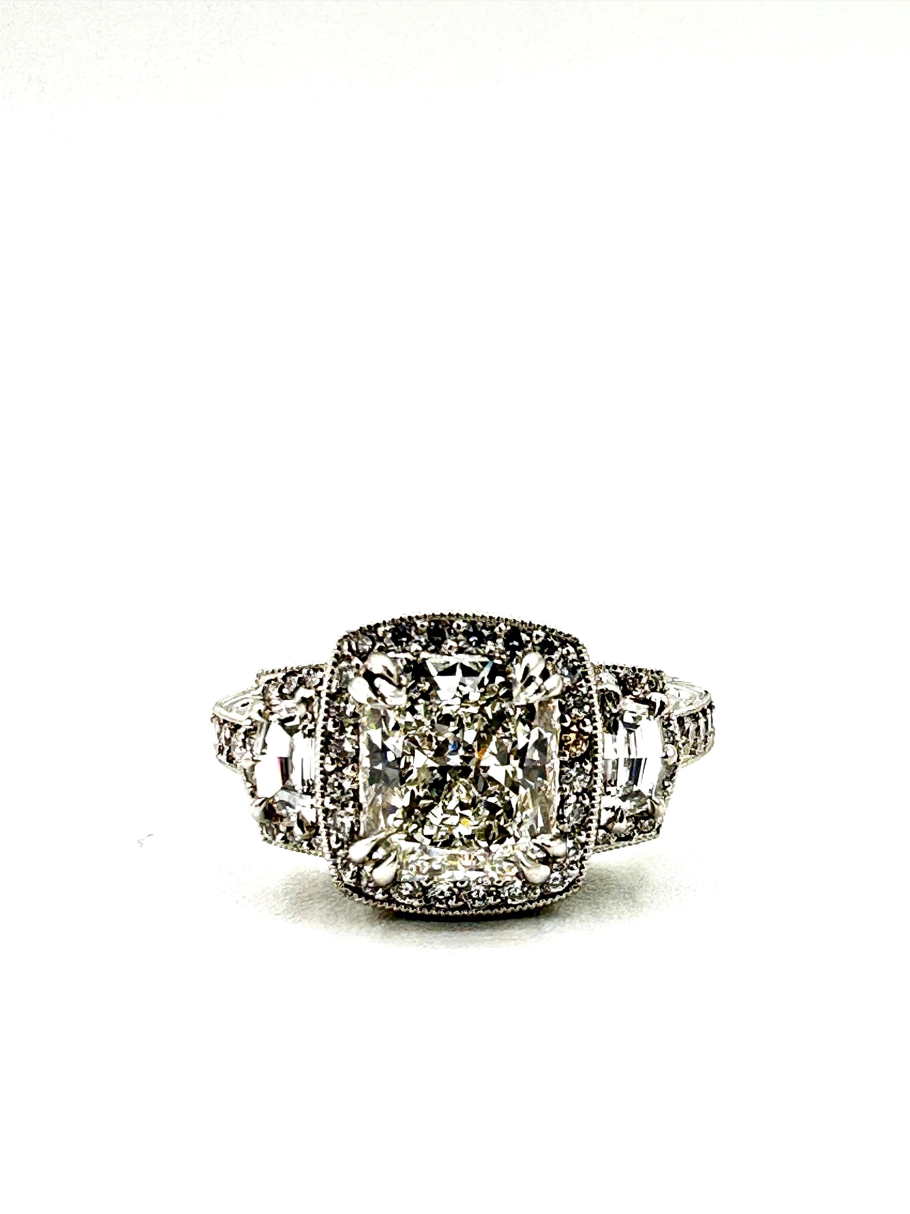 There is so much light return from this ring that it is blinding!  The center radiant cut Diamond is with four double claw prongs, surrounded by a single row of round brilliant Diamonds, with a single Cadillac cut Diamond on each side, and three