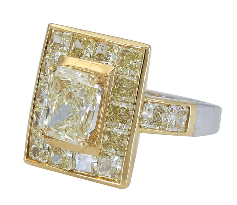 A color-rich and unique engagement ring style showcasing a 2.01 carat brilliant radiant cut yellow diamond, surrounded by a single row of vibrant radiant cut yellow diamonds. Diamonds are channel set in 18k yellow gold in a white gold shank. 
Yellow
