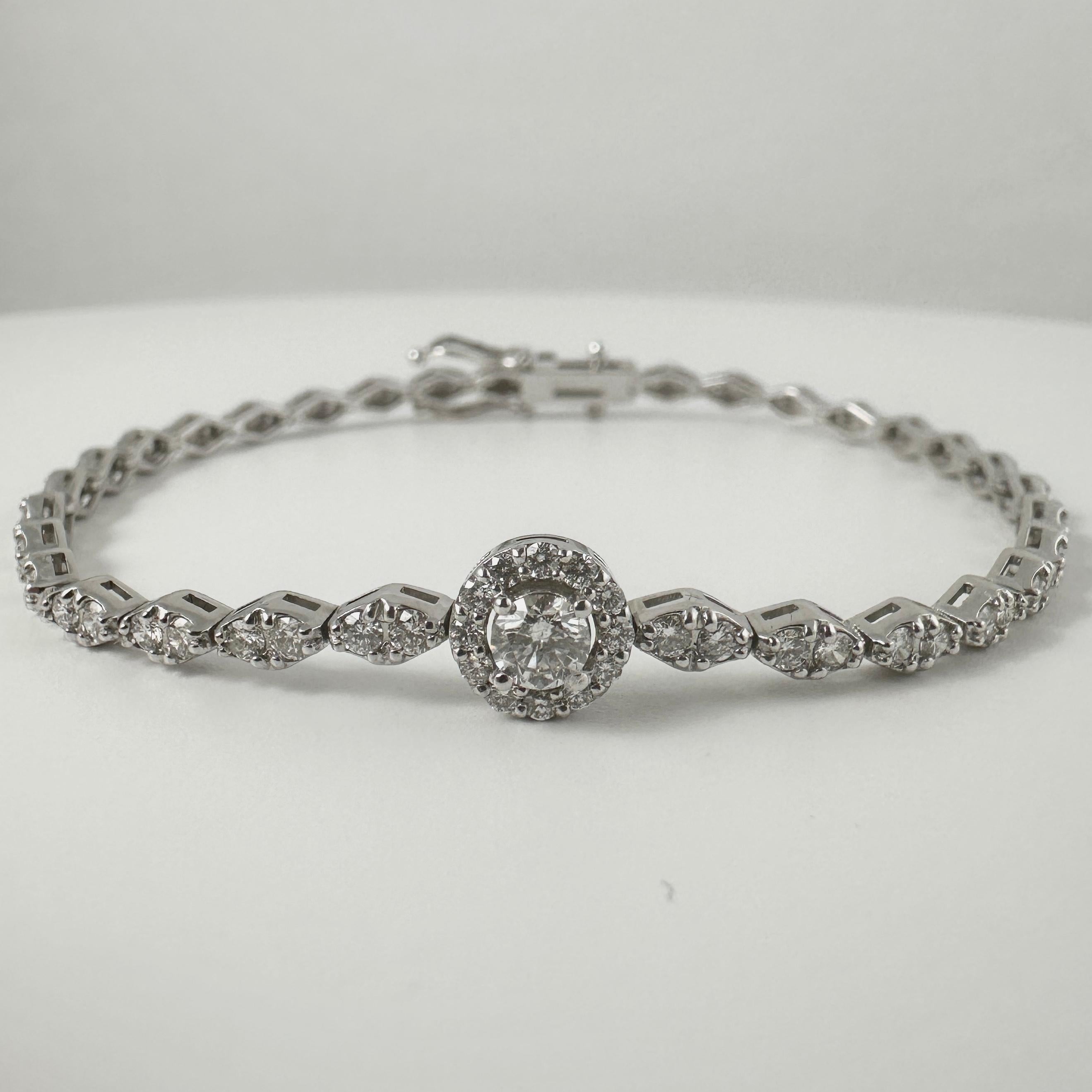 This refined bracelet showcases a round brilliant-cut diamond center of 0.25 carats, carefully selected for its sparkle and fire. Surrounding the center is a delicate halo of round diamonds in G-H color and SI clarity, amplifying the brilliance of