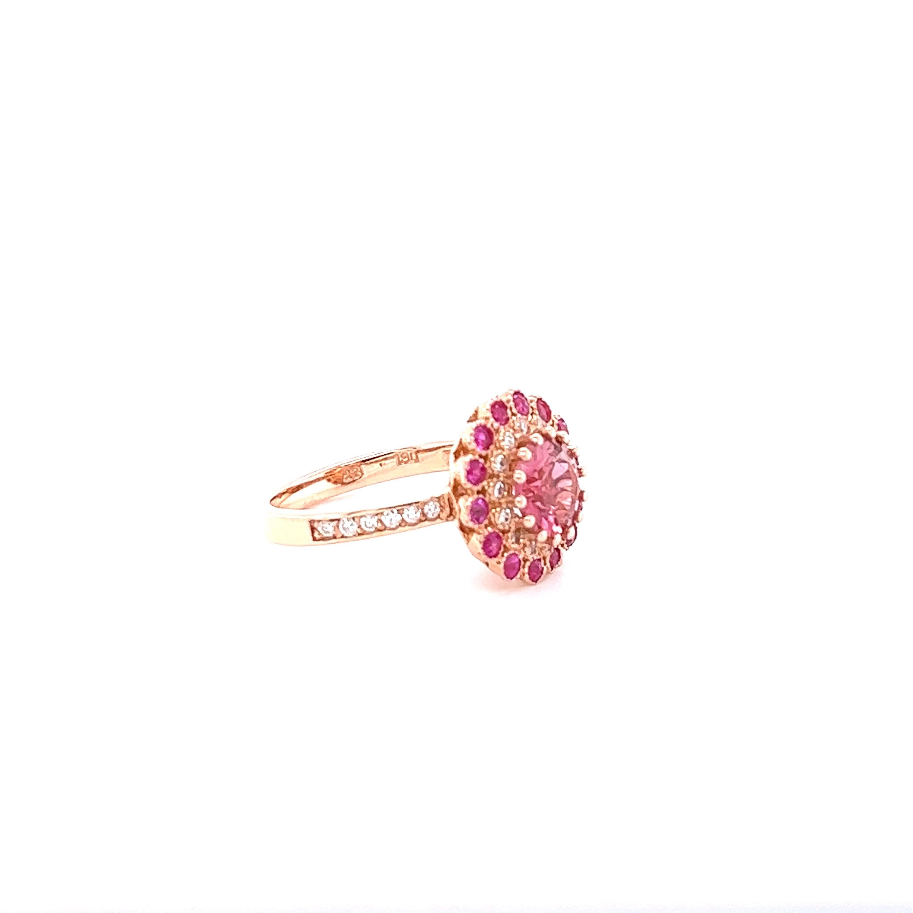 Esta belleza tiene una Turmalina Rosa de talla redonda engastada en el centro del anillo que pesa 1,79 quilates y mide 8 mm.  Está rodeada por 14 zafiros rosas talla redonda que pesan 0,54 quilates y 26 diamantes talla redonda que pesan 0,27