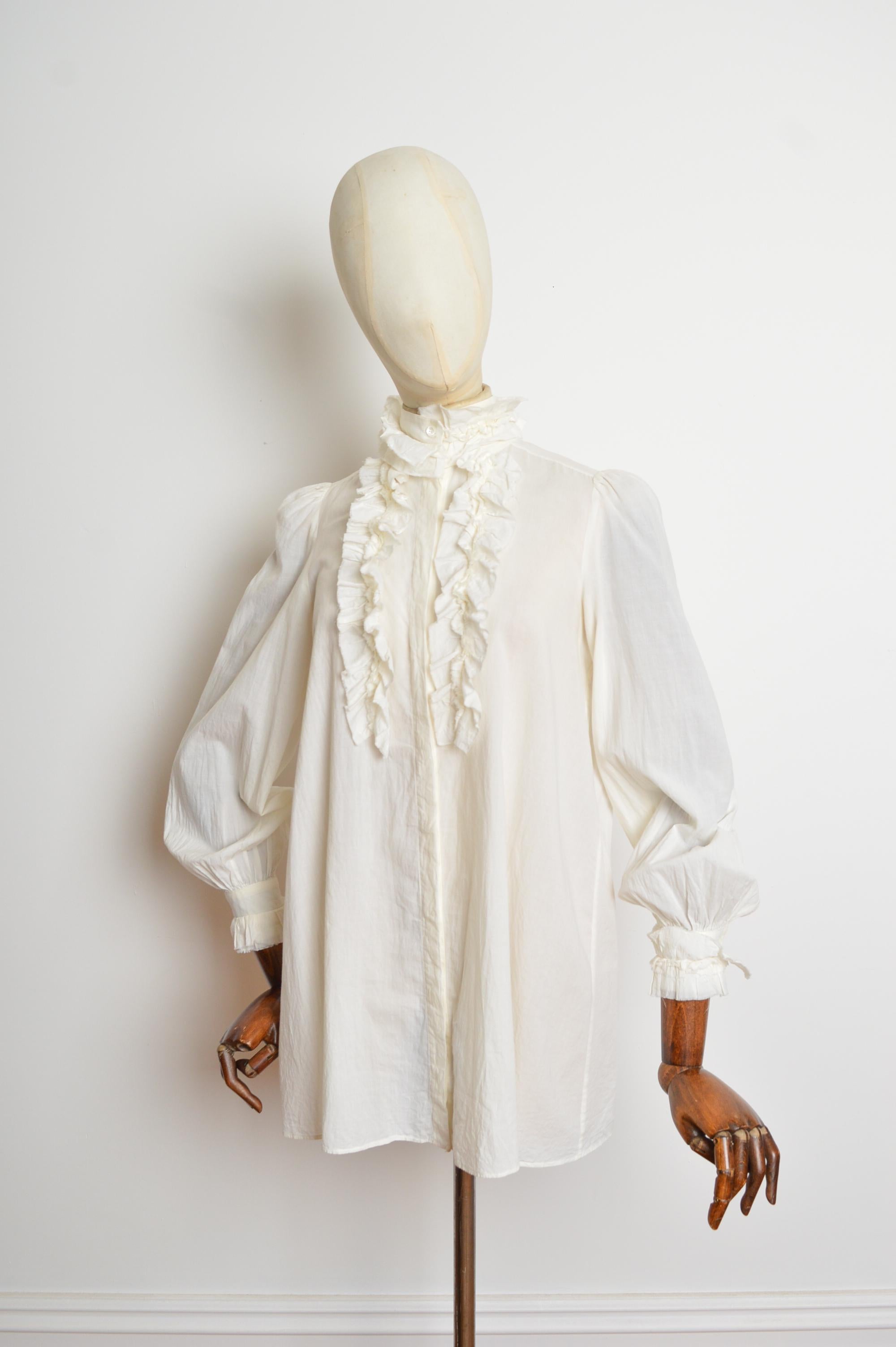 Blusa Alexander McQueen 2010 de estilo victoriano, con cuello vuelto, botones en la parte delantera y mangas largas. 
Etiqueta de talla ; EU 40 / Talla recomendada U.K. 8-12
Las medidas se indican en pulgadas ('')
De foso a foso; 19