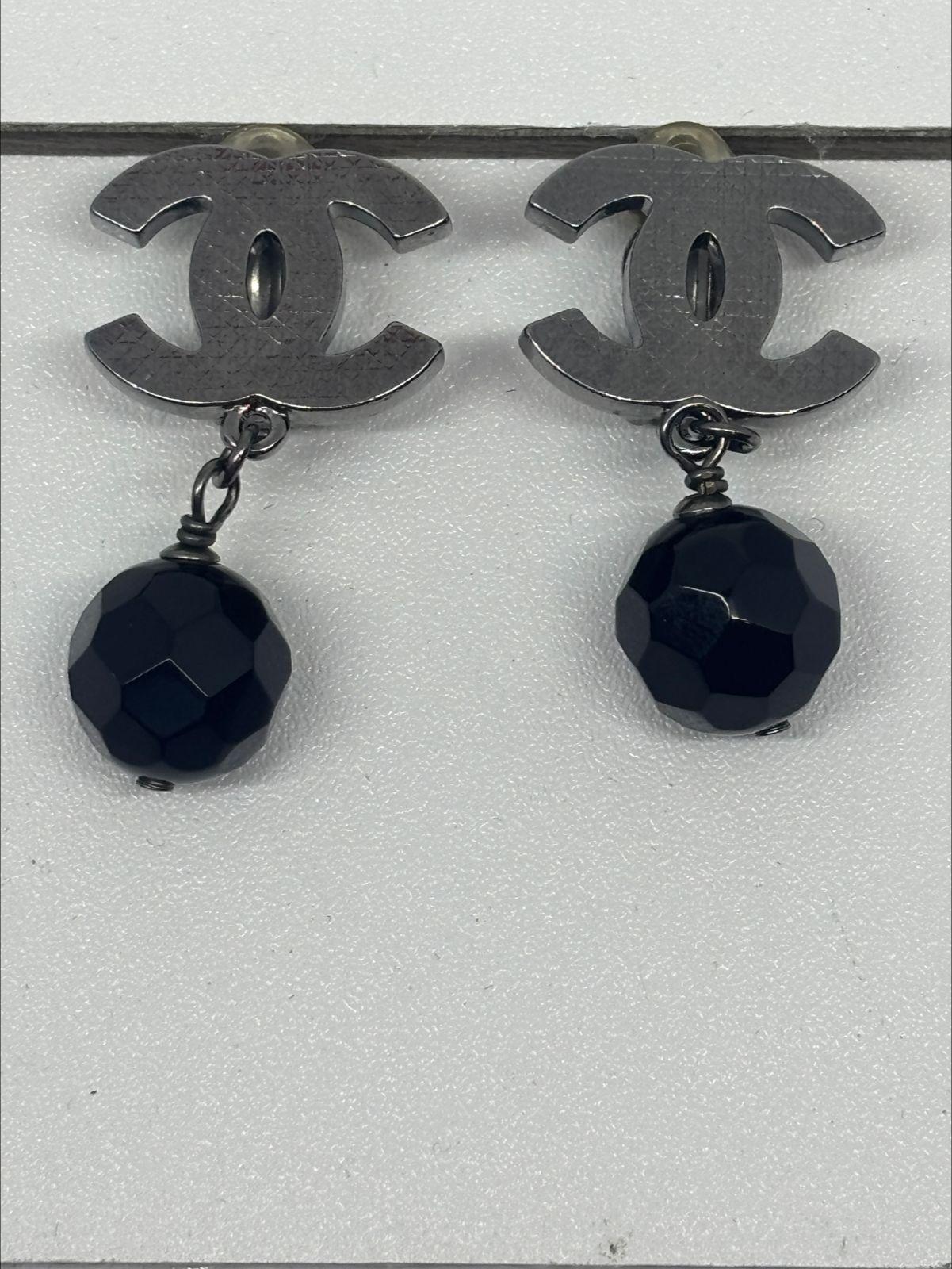 Classic chanel silver cc earrings with black dangling crystal. Slight cannage texture on the cc hardware. Overall still in good condition, slight yellowing to the plastic pad. Still sturdy. Comes as is with replacement dust bag.