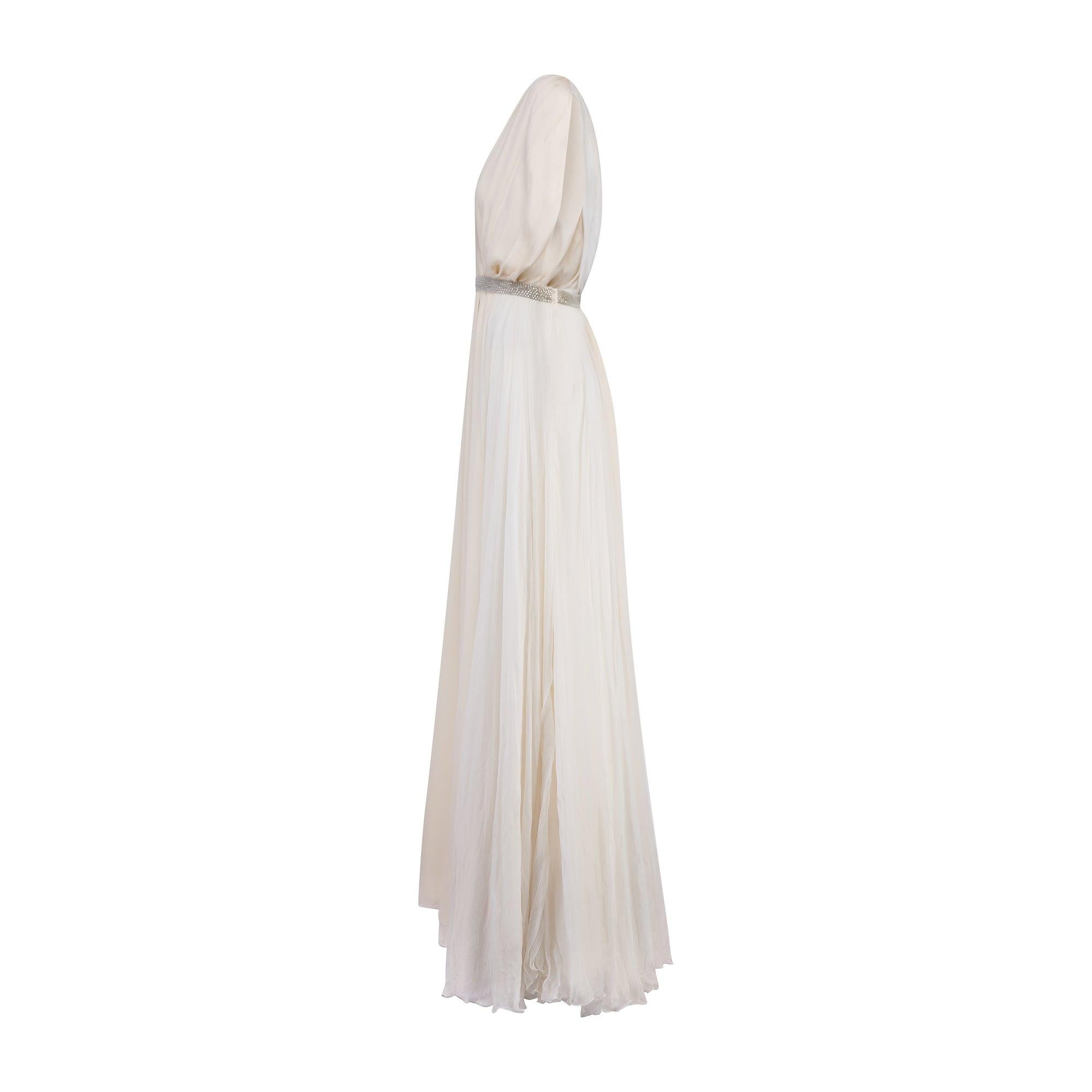 This romantic dress was designed by Hannah MacGibbon for Chloé Fall 2010, and may have been part of a capsule collection. It is tailored from off-white or ecru coloured sheer silk chiffon and matte silk and falls to floor length. It has an