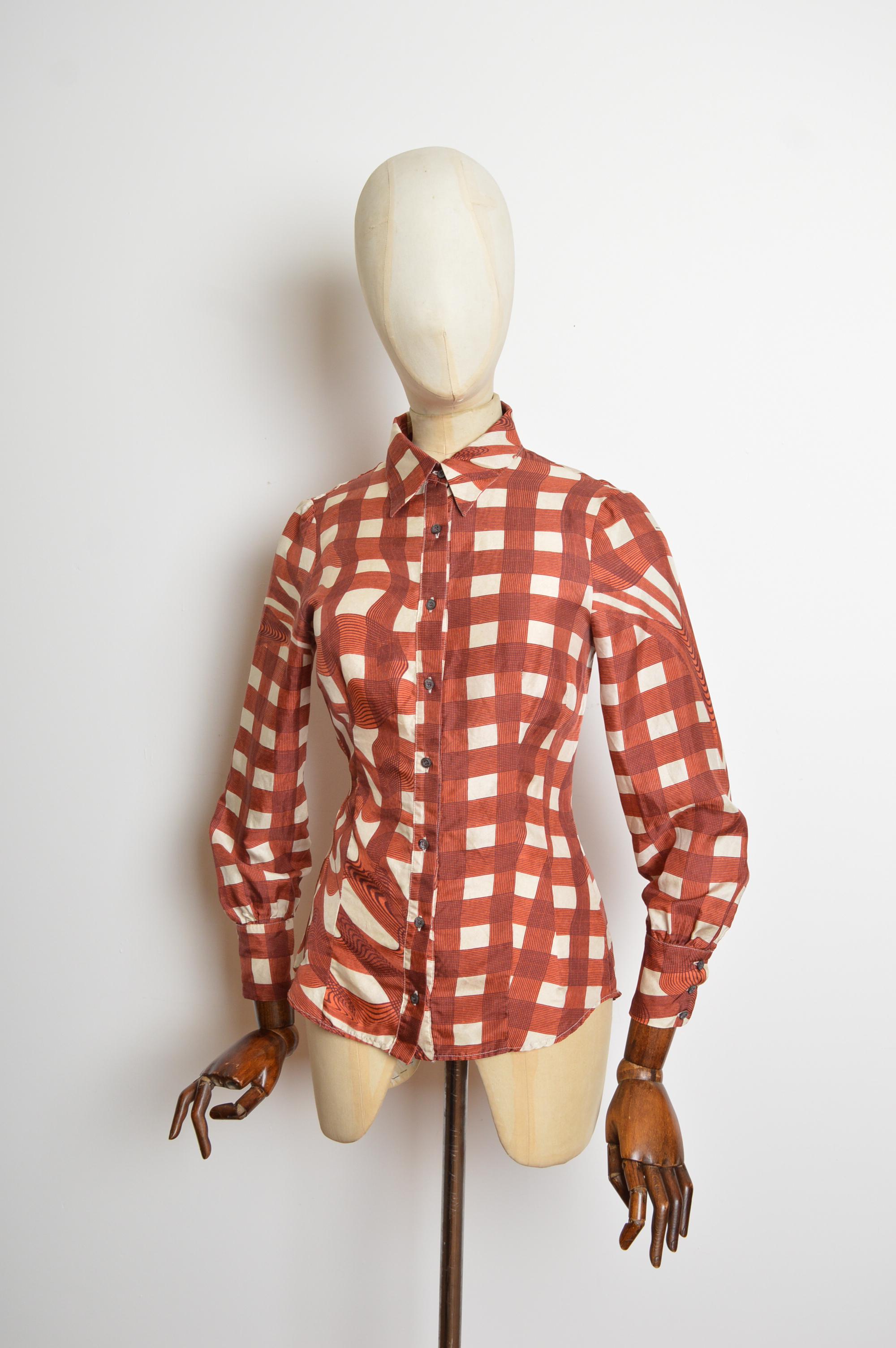 Blusa de seda pura Otoño 2010 de Miuccia Prada con un precioso estampado de cuadros psicodélicos en tonos cobre y crema. 
Tiene mangas largas, silueta ajustada y botones en la parte delantera. 
Talla; Talla recomendada U.K. 6 
Las medidas se indican