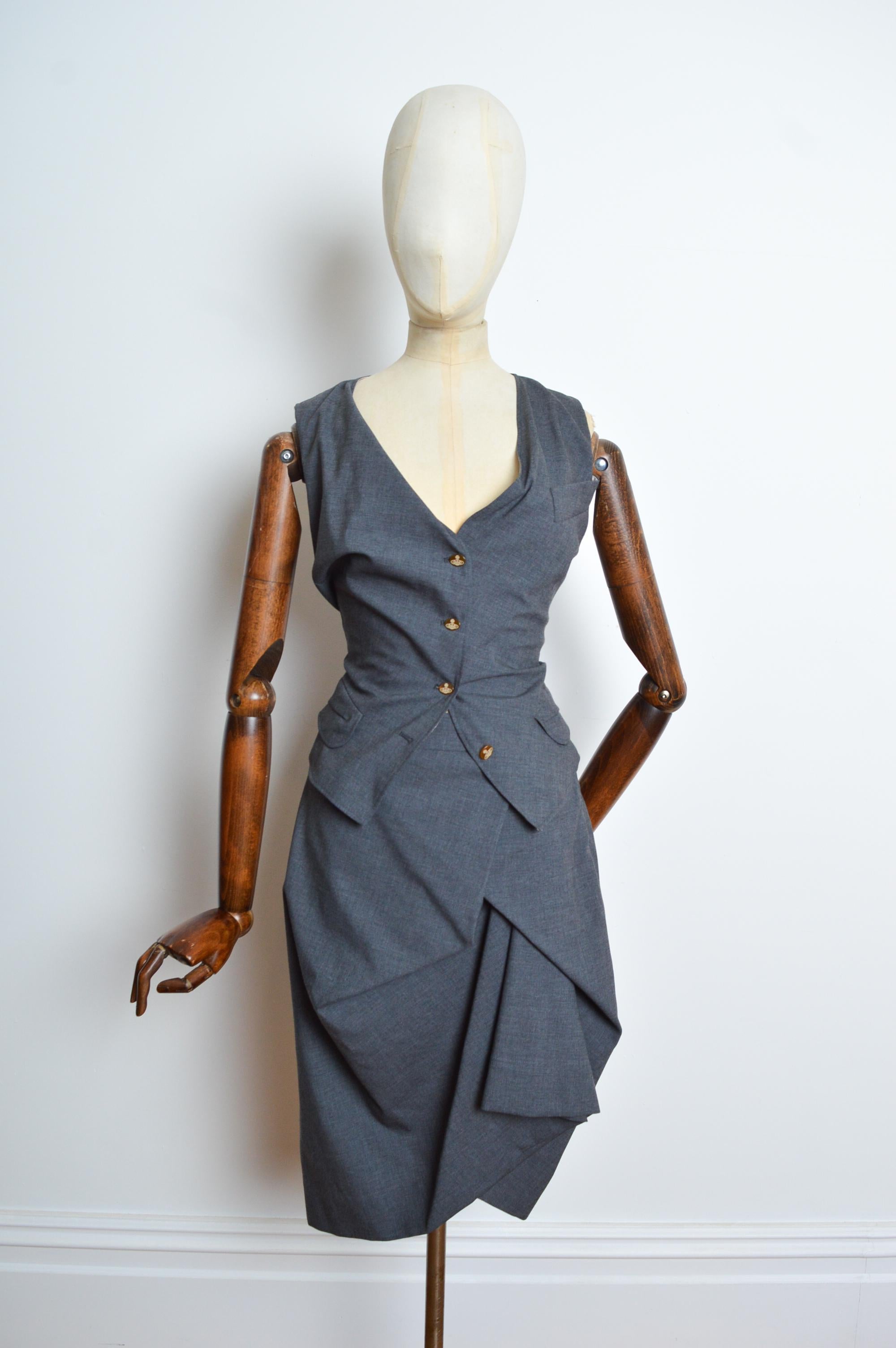 Superb 2010 Vivienne Westwood ready to wear ensemble in charcoal grey featuring a fitted almost corset-like waistcoat and avant guard ruched pencil skirt.
The garments are both beautifully lined in the signature ballet slipper pink jacquard with