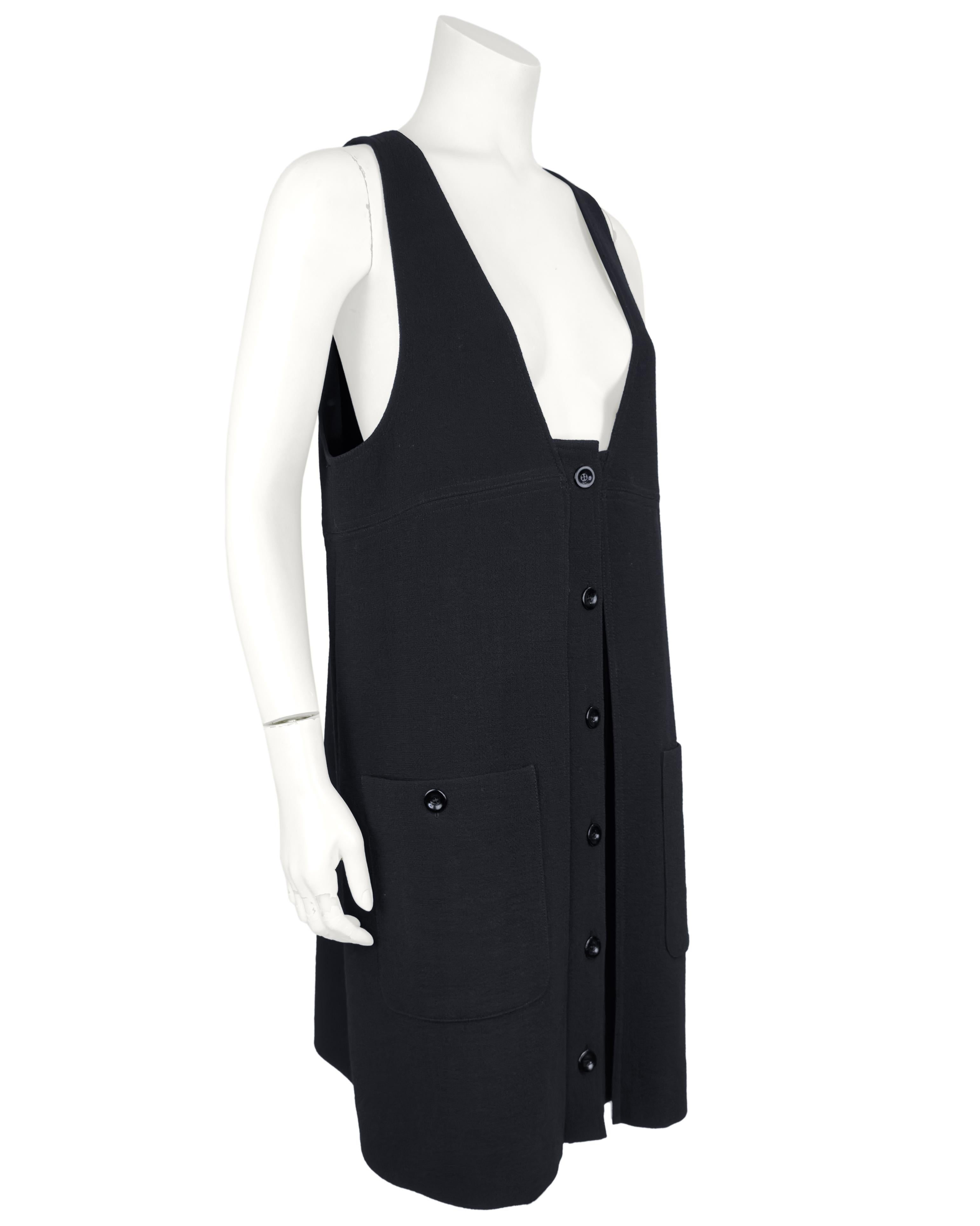 Modèle phare de Chloé tout au long des années 2000, cette chasuble en laine noire boutonnée sur le devant a été portée sur le podium avec une blouse blanche fluide en dessous. Deux grandes poches plaquées sur le devant se ferment à l'aide de boutons