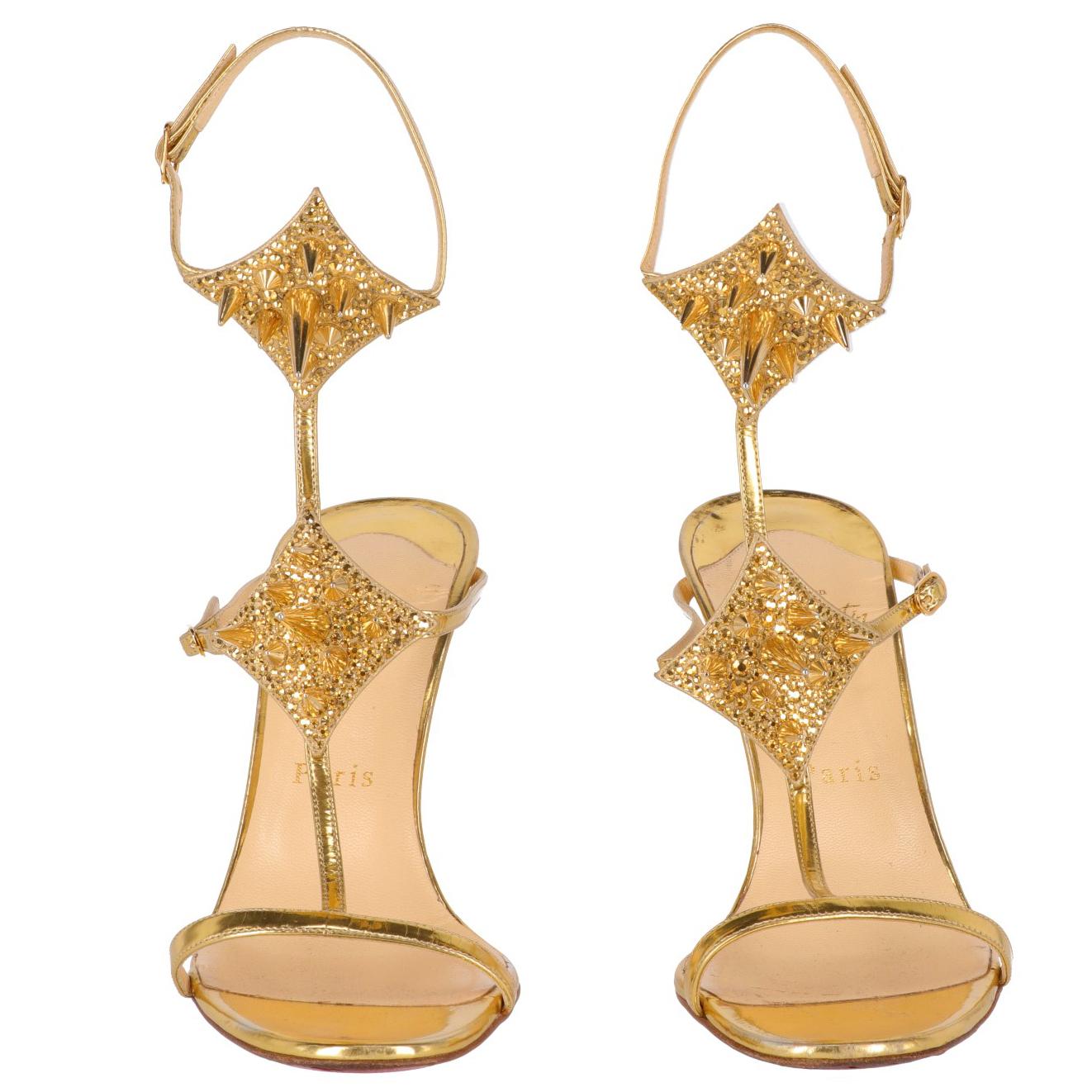 
The glamour Christian Louboutin gold-tone leather sandals feature a 11 cm high spike heel, an ankle string fastening and embellished by studs and rhinestones. 
The item shows some signs of wear on the insoles and light scratches at heels, as shown