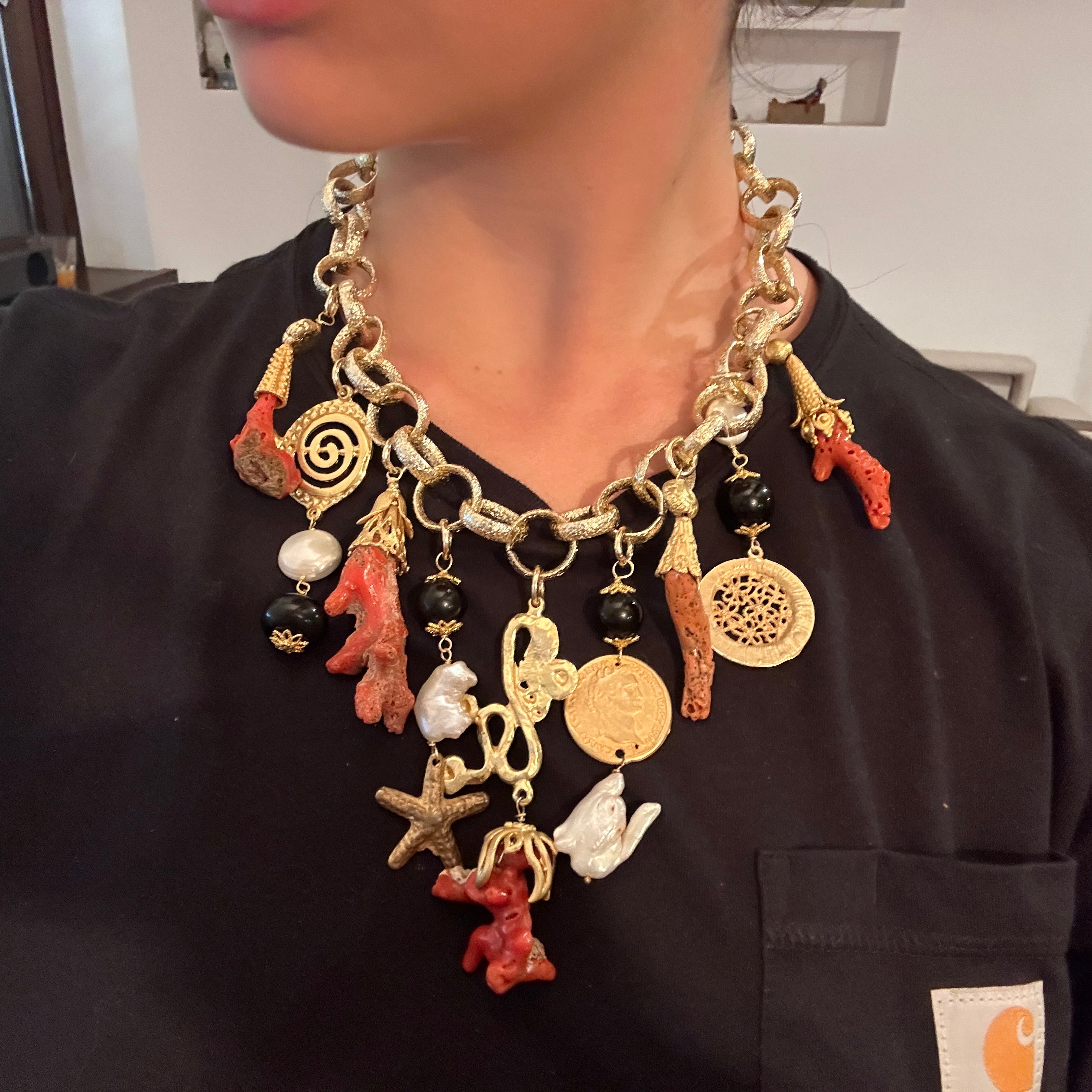 The necklace is constructed from brass links, featuring a medium-sized chain that serves as the foundation for an array of dangling charms.
The necklace includes a variety of charms made from different materials. The most prominent are the pieces of