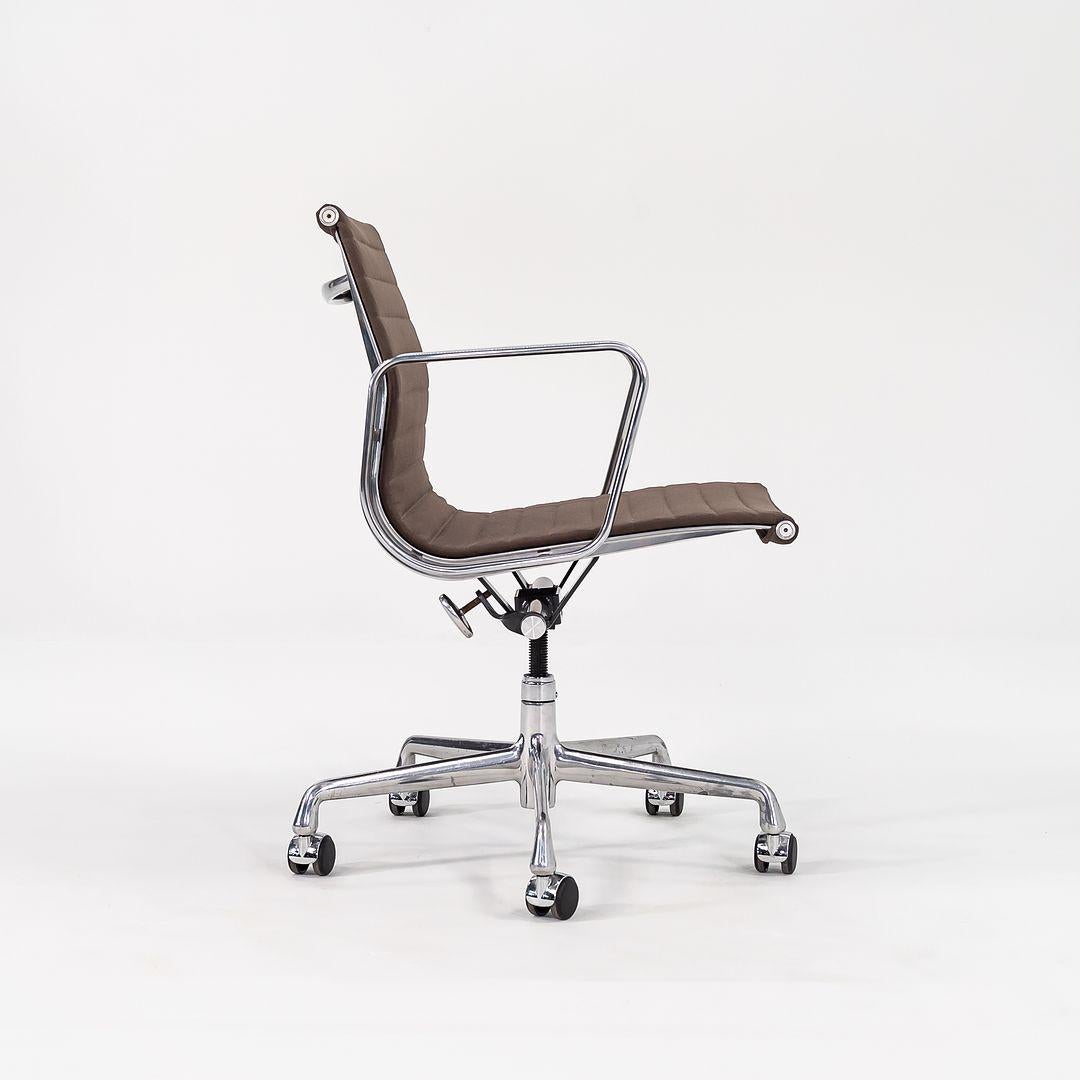 This is an Eames Aluminum Group Management Desk Chair, model EA335, originally designed by Charles and Ray Eames for Herman Miller in 1958. This example was produced in the 2010s. The design features an aluminum frame, and its upholstery is done in