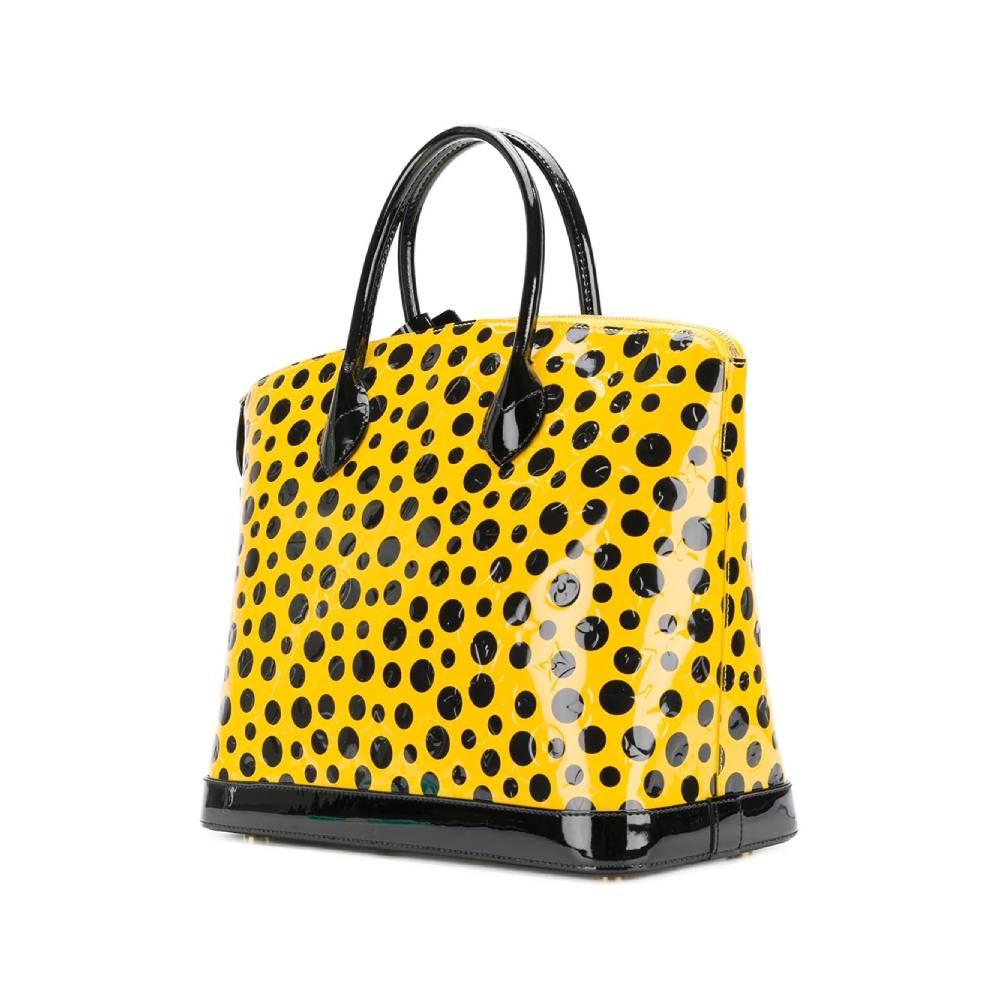 Lock It Louis Vuitton bag designed by Yayoi Kusama, in yellow patent leather with black polka dots with round handles, top zip closure, golden padlock and keys. Inside there is a main compartment and a zip pocket, feet at the base, golden metal