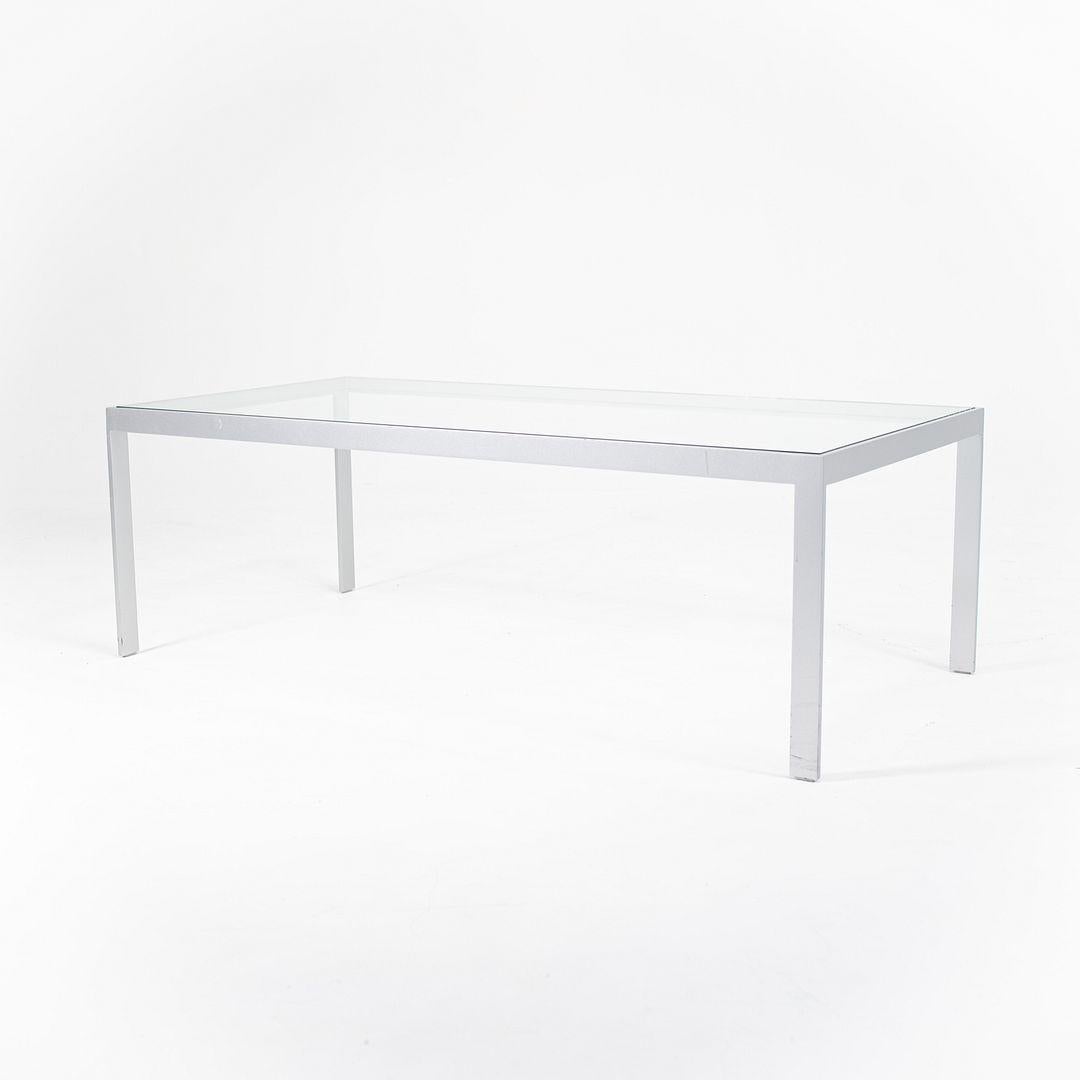 Si tratta di un tavolino da caffè prodotto negli anni 2010 da un designer e produttore sconosciuto. Il tavolo presenta una struttura in acciaio opaco dalle linee pulite e rettilinee, che sostiene un piano in vetro trasparente. Minimalista nella