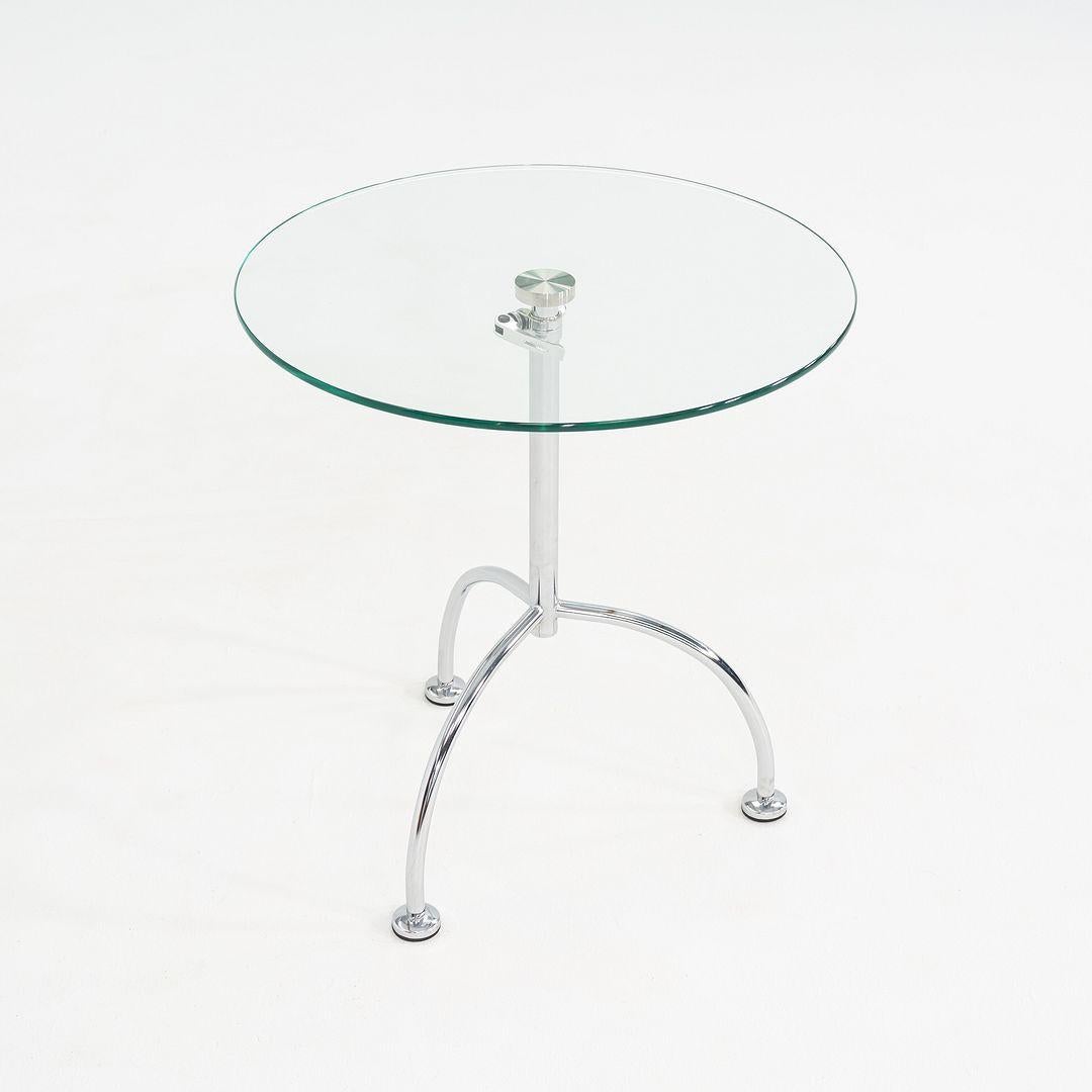This is a pair of chromed steel and glass sides tables. The designer and manufacturer are unknown, but the pieces date to the 2010s. Their design features an adjustable base. The listed price includes both tables to be sold together as a pair. 
 
