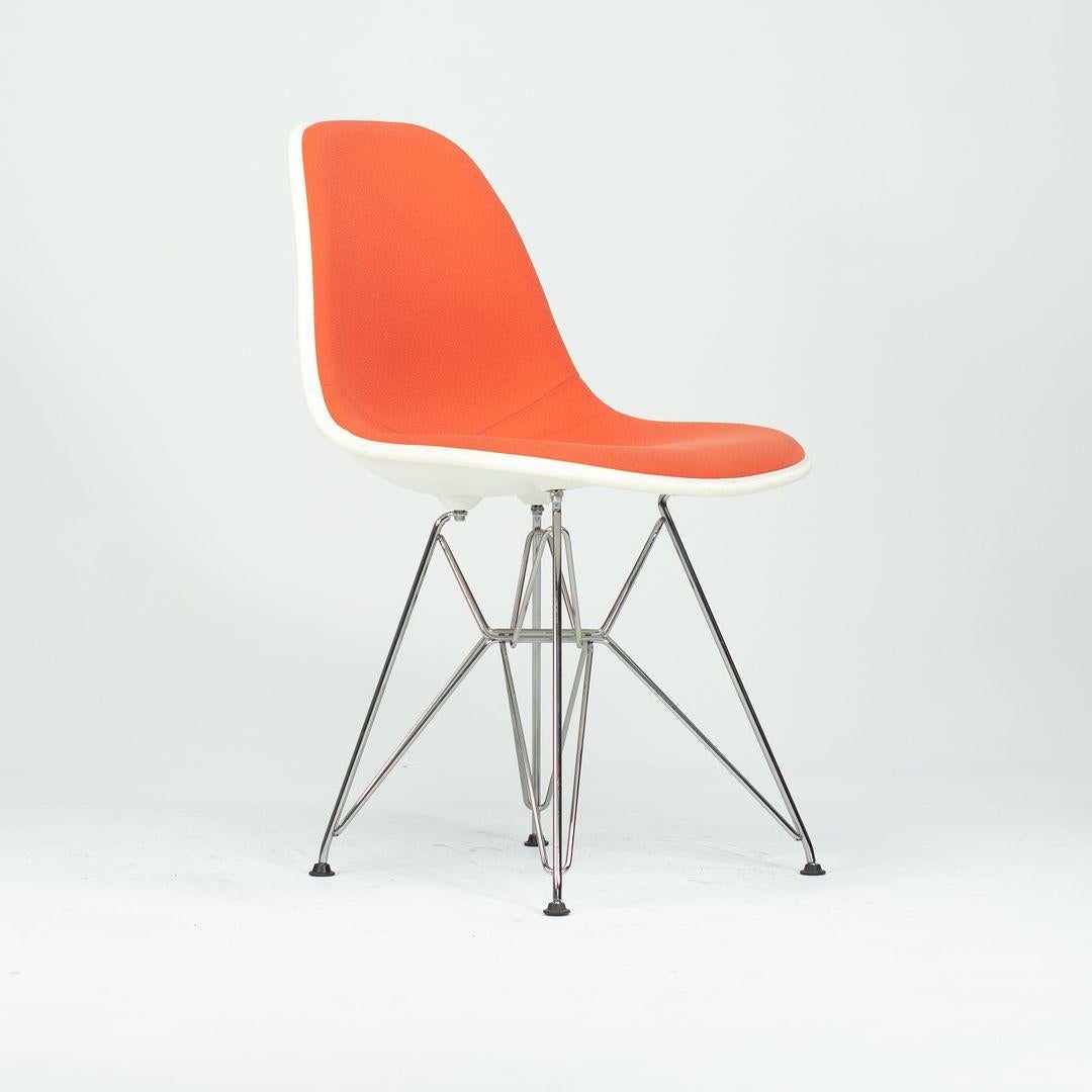 Il s'agit d'une paire de chaises Shell en plastique, tapissées en orange, avec des bases Steele, fabriquées en acier avec une finition chromée. Ce style a été conçu par Ray et Charles Eames, et ces chaises ont été produites par Herman Miller aux
