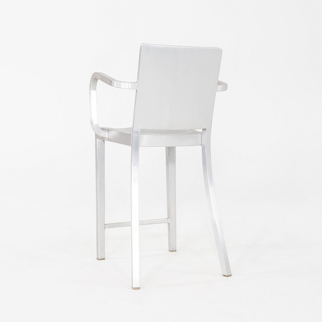 Il s'agit d'une paire de tabourets de comptoir Hudson avec accoudoirs, conçus à l'origine par Philippe Starck en 2000. Ces exemples particuliers ont été produits par Emeco aux États-Unis et datent des années 2010. Les tabourets sont entièrement